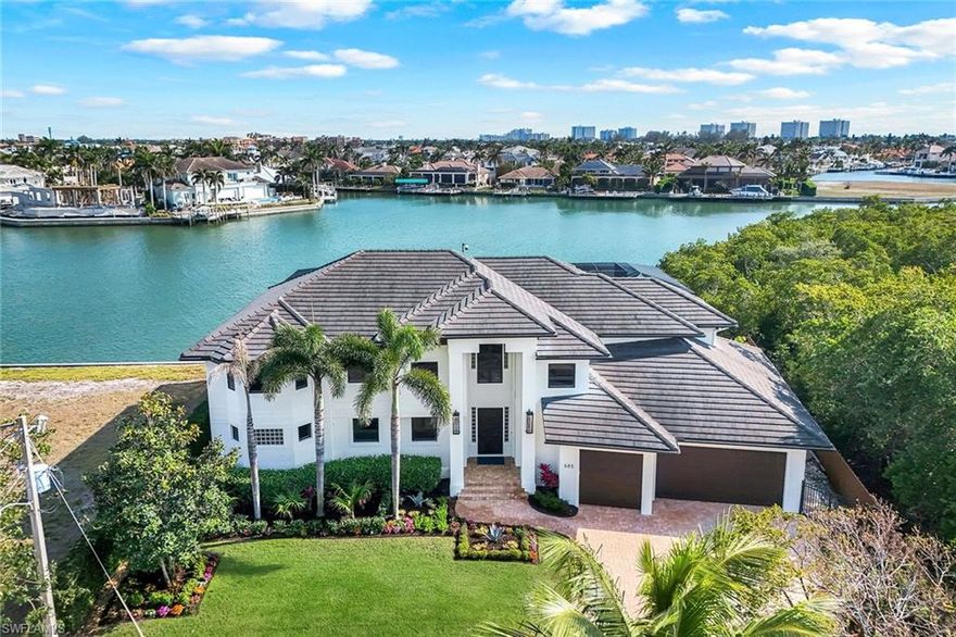 An exquisite waterfront haven on its exclusive cove, this one-of-a-kind residence boasts an unparalleled setting adjoining a protected natural shoreline that is safeguarded from any future development. The property offers sweeping wide water bay views and quick direct access to the Gulf, making it a paradise for yacht enthusiasts. The expansive dock is the centerpiece of this waterfront haven, equipped with two boat lifts and two jet ski lifts, catering to the avid boaters' and fisherman's every need. Imagine the luxury of relaxing beneath your tiki hut, watching an abundance of wildlife in their natural habitat. The resort-style veranda area is designed for ultimate relaxation and entertainment. It features a covered lanai, infinity pool with spa and waterfall, a bar with a built-in gas grill, and pool bath. This outdoor oasis is ideal for hosting gatherings or simply unwinding in your private retreat. Architectural mastery, this stunning home offers five bedrooms, four full baths and three half baths, encapsulating over 4,900 square feet of air-conditioned living space. Upon entering, you are greeted by a light-filled, open great room that seamlessly blends into a beautiful wet bar, separate dining area and gourmet kitchen. The kitchen is a chef's dream, complete with a breakfast bar, a gas cooktop, a built-in electric wall oven, walk-in pantry and an abundance of granite countertops. The downstairs primary suite retreat provides breathtaking views and a sense of tranquility. Additionally, there is a half bath on the ground floor for convenience. The second floor, accessible via a private elevator, features an expansive loft with another wet bar, equipped with wine cooler, and a den/sitting area. The second primary suite retreat and three additional bedrooms offer ample space for family and guests. A private balcony leads to an observation deck, providing sprawling 360-degree views, and an ideal advantage for enjoying the surrounding natural beauty and stunning sunsets. The residence is adorned with exquisite details, including custom Brazilian cabinetry, tile and luxury vinyl floors, a highly engineered two-story screen enclosure and an abundance of additional storage. The four-car garage, impact windows and doors, electric shutters, and Terex decking further enhance the home's functionality and durability. This gorgeous home embodies the essence of paradise living. With its unique location, luxurious amenities and thoughtful design, this residence is not just a home, it is a lifestyle. This is what living in paradise is all about.