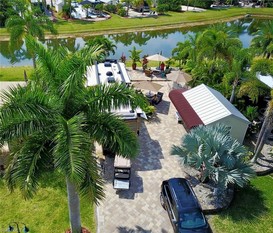 Lot 141 is a private retreat tucked along a quiet street, making a striking first impression the moment the paver drive welcomes you home. Thoughtfully designed raised pavers frame manicured flower gardens, filled with stone for long-lasting curb appeal and minimal seasonal upkeep. The coach house is a true tropical escape, featuring a poured concrete floor topped with light wood-look plank tile that keeps the space bright and inviting. Inside, a colorful pull-out sofa adds comfort for guests, while the well-lit kitchenette is ideal for morning coffee or easy meal prep. You’ll find a large refrigerator, microwave, stainless steel sink, and crisp white cabinetry with ample storage for entertaining essentials. A neatly tucked washer and dryer closet, along with two additional storage closets, keeps everything organized and out of sight. The bathroom offers a shower with an etched glass door, open shelving for added storage, and a charming sink. Just outside, the raised lanai becomes the natural gathering place, perfect day or night. A firepit adds warmth on cooler evenings and creates a glowing ambiance for relaxed conversations while overlooking the water. Mature palms and multiple planters provide shade and endless opportunities to enhance the property with your favorite tropical touches. Be sure to ask the agent about outdoor furniture that may convey. Life at RiverBend Motorcoach Resort flows effortlessly with the rhythm of the Caloosahatchee River. Sweeping water views and cooling river breezes set the tone for peaceful mornings, vibrant sunsets, and days that unfold at just the right pace. The river is more than a backdrop, it’s part of everyday living. The River Clubhouse (open seasonally) is the social heart of the community, hosting live music, themed dinners, trivia nights, and gatherings where friendships come naturally. Creative energy fills the Creations Clubhouse with hands-on classes and shared passions. Sun-filled afternoons center around the resort-style pool and cabana bar, while mornings begin with pickleball, fitness classes, or scenic walks. Evenings bring glowing skies, laughter, and connection—clear reminders that RiverBend isn’t just a place to stay, it’s a lifestyle you’ll never want to leave. It’s the rare Luxury RV Motorcoach resort that feels instantly familiar yet endlessly special and one visit is never enough.