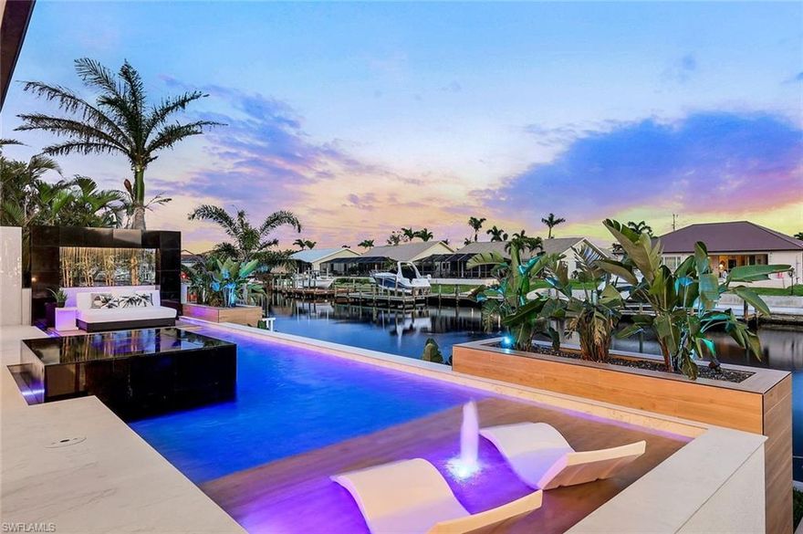 Cape Harbour area Luxury New Construction Waterfront Home Professionally Decorated and comes Fully furnished by Norris Furniture and Interiors. Featuring 3,749 SF with 4 Beds, Office, 6 Baths. Porcelain Driveway & 3 Car Garage w/ Modern Impact Glass Garage Doors. Entertain guests in the ventilated Cigar Bar and Lounge with Wine Cooler & built-in Humidor! Open living space with 15' designer coffered ceilings, feature wall & fireplace, all overlooking the pool & water. The celebrity style pool feels like a waterfront Five Star Resort! Huge Porcelain lanai w/ heated pool, infinity hot tub, sun shelf, and waterfall splashing down! Tons of deck space for sunbathing & entertaining. Even a sunken waterside firepit. Open kitchen with 12' waterfall island and custom skinny shaker cabinetry completed with a Gas Range, Built-in oven & Espresso maker, walk-in butler's pantry! Waterfront Owner's Suite with Spa Bathroom featuring tub, shower, Toto Smart toilet, and large closet. 4 Suites with private baths, large closets, and unique coffered ceilings. Outdoor living room poolside "Cabana" & outdoor kitchen. SOUTH EXPOSURE-DIRECT BOATING ACCESS the most daytime sunlight on the pool!