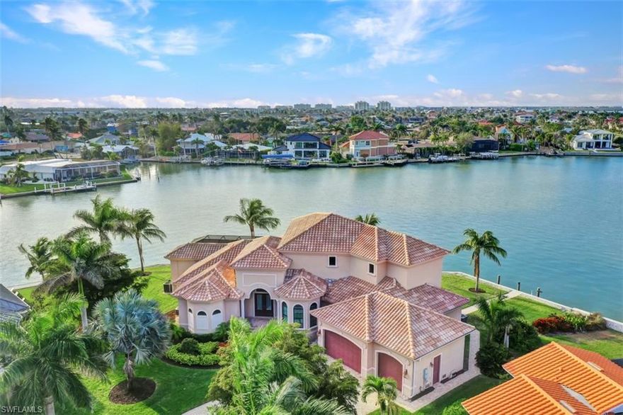 Stunning wide bay views from this tip lot home with a 224 ft wrap-around seawall (2012), 115 ft covered, screened lanai & grassy yard. This water direct coastal contemporary home of 4 Bed | 4.5 Ba | 3617SF, is on a cul-de-sac of nearly 1/2 an acre (.49). Enjoy the shallow beach pool, waterfall spa, outdoor shower, kitchen and grill. The great room open plan living, dining, kitchen and 4 ensuite bedrooms overlook the water. The kitchen features a breakfast bar, pantry closet, built-in desk and dining area. The private primary ensuite features 2 walk-in closets and bath with separate vanities, soaking tub, and walkthrough shower plus a 2nd ground floor ensuite. 2 upper ensuite beds share a common living room with wet bar & built-in entertainment center and all access a waterfront terrace. Enjoy a roomy, airy feeling with high, volume, tray and box beam ceilings, recessed lighting, impact windows and doors, and 3 zoned A/C.. The 3-car garage has room for a 4th, including loading space and parking in drive. Tropical landscaping features majestic Royal Palms. This ultimate light and bright entertainers’ home is perfect for indoor/outdoor waterfront living.