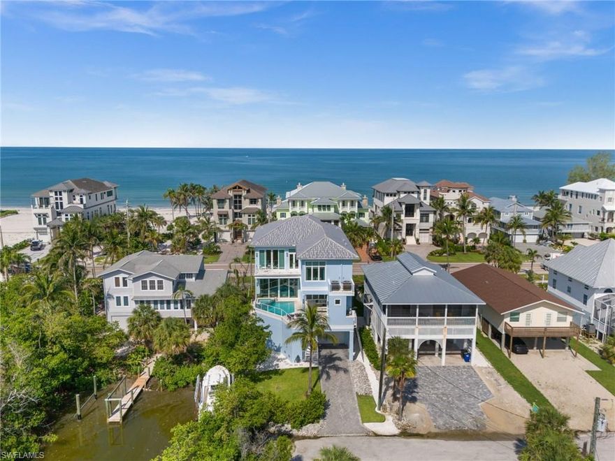Coastal luxury meets laid-back island living in this beautifully designed 2019 multi-level home, perfectly positioned just steps from the quiet, uncrowded shores of Little Hickory Island in Bonita Springs. A true gem for beach lovers and boaters alike, the property offers direct Gulf access in minutes from its private boat dock. A major standout feature is the first-floor elevation of 21 feet, including the pool, spa, and all pool equipment—also at 21 feet. This elevated design not only provides exceptional protection from storm surge, but also enhances everyday living. Unlike typical builds where the pool sits 20+ feet below the main living area, this home offers seamless indoor-outdoor flow, with the saltwater pool and spa on the same level as the kitchen, living, and dining spaces—a rare and valuable layout. Light-filled and thoughtfully styled, the home features soft coastal hues of blue and white, paired with warm hardwood floors and natural textures throughout. With 4 bedrooms plus a dedicated office or optional 5th bedroom, there’s space for everyone to relax and unwind. The second-floor lanai offers an exceptional indoor-outdoor experience, complete with a saltwater pool and spa, outdoor kitchen, gas fireplace, sitting area, pool bath, and retractable hurricane screens—perfect for year-round entertaining or quiet evenings at home. Inside, enjoy 12-foot ceilings, shiplap accents, and a gas fireplace that add depth and character. The chef’s kitchen is outfitted with premium WOLF, SubZero, and Bosch appliances, a spacious island, butler’s pantry, and three laundry zones for ultimate convenience. This home is being offered turnkey furnished, including stylish pieces by Norris Furniture, as well as all bedding, linens, dishes, silverware, artwork, and decorator accessories—everything you need to move right in or begin generating rental income immediately. An elevator provides easy access to all levels. The third-floor primary suite feels like a private retreat, featuring a tray ceiling, spa-inspired bathroom with dual vanities, and a serene balcony with Bay views. Each of the additional guest suites includes its own bathroom, and a central wet bar makes this level perfect for relaxing. A rare 4+ car garage with front and rear entry offers pull-through ease—ideal for cars, golf carts, or boat storage. Whether you're looking for a full-time island residence or a high-performing vacation rental, this exceptional property delivers on both lifestyle and peace of mind, and even includes a transferable flood insurance policy. Just 35 minutes from the Southwest FL Airport and a short drive to Coconut Point, The Promenade, Mercato, and 5th Avenue—this is coastal Florida living at its finest!