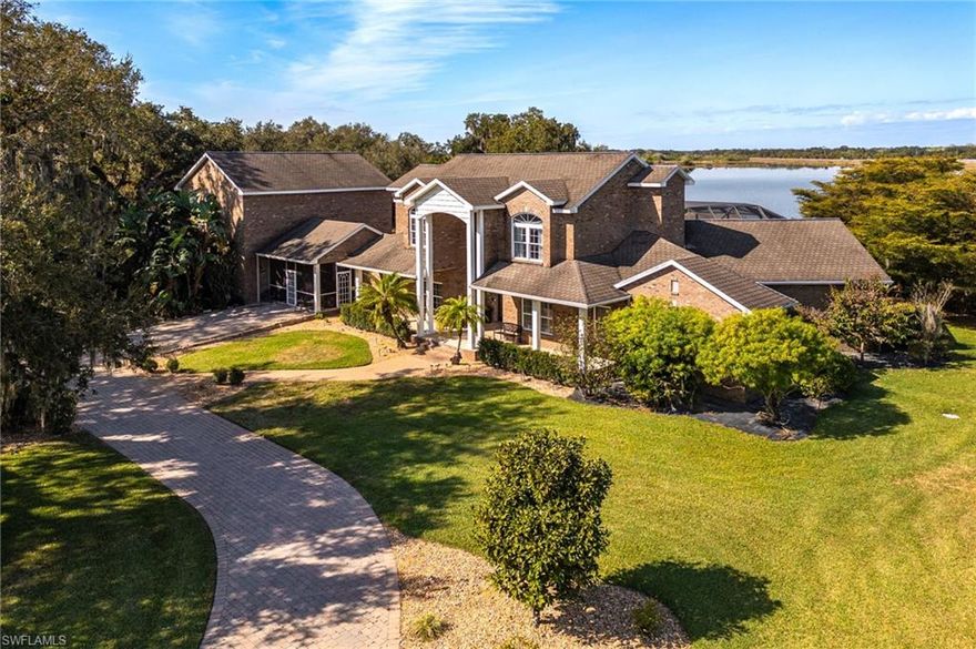 Welcome to this exceptional two-story brick residence in beautiful LaBelle, FL offering approximately 8,450 square feet of refined living space. This 4-bedroom, 3.5-bath estate is beautifully landscaped and features gated entry, a circular paved driveway, and tranquil lake views.
Upon entry, the foyer is highlighted by a vintage Swarovski crystal chandelier and opens to a formal living room with a dramatic rock fireplace and triple-arched window overlooking the pool and lanai. A private office with wood floors and vintage glass double doors sits just off the foyer, along with a formal dining room featuring wood floors, an elegant chandelier, and large front-facing windows.
The gourmet kitchen features granite countertops, a rock-accented bar, stainless steel appliances including an ice machine and trash compactor, center island, double sinks plus prep sink, soft-close cabinetry with slide-out shelving, accent lighting, glass display cabinetry, and a walk-in pantry. The adjacent family room opens through double glass doors to a sunroom and seamlessly connects to the outdoor living space.
The first-floor master suite is a luxurious retreat, complete with a fireplace, ceiling fans, darkening blinds, and oversized his-and-her walk-in closets. The spa-inspired master bath includes a soaking tub with stained-glass accent window, a glass-enclosed shower with body jets, rain head, and handheld shower, dual granite vanities, a makeup vanity, tile flooring, and custom cabinetry.
Upstairs are three spacious bedrooms, all with wood floors and walk-in closets, plus a full bath with double vanities and a tub/shower combination.
Enjoy resort-style living with a heated pool, sheer descents, lighting, and stunning lake views. The stone-paved lanai includes an outdoor cooking and entertainment area, with a paved walkway leading to a firepit.
Additional features include a half bath with vintage accent sink, a spacious laundry room with granite countertops and storage, a screened patio, and a two-car garage. Above the garage is a large game room or apartment with full bath, mini kitchen, bar, and entertainment space.
A 2,160 sq. ft. (36’ x 60’) detached brick garage/workshop/outbuilding adds exceptional versatility, featuring two 14’ x 9’ garage doors and a separate entrance leading to a small office or workroom—ideal for storage, hobbies, or business use. The grounds are fully landscaped with Florida trees, river rock accents, sprinkler system, outdoor lighting, and gated access.
Set in the serene countryside of LaBelle, this estate offers refined privacy, expansive views, and a true sense of retreat surrounded by natural beauty. Known for its wide-open spaces, riverfront charm, and understated elegance, LaBelle provides a peaceful lifestyle while remaining within comfortable reach of Fort Myers, Naples, and Southwest Florida’s premier dining, shopping, and coastal destinations.