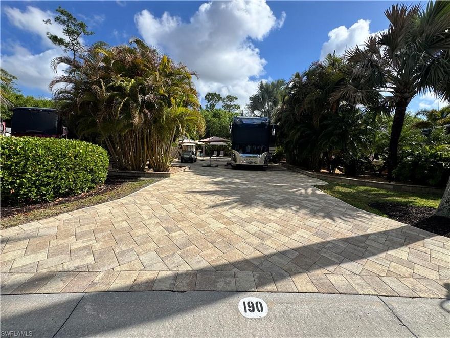 Lot 190 – Live Where the Action Is. This lot puts you right where the energy lives, close enough to all the fun that you can join in at a moment’s notice, but with your own beautifully designed space to retreat to when you’re ready to kick back. The coach house is bright and welcoming, with two sets of doors that swing open and invite that famous Florida sunshine straight inside. It feels airy and easy. You’ve got a kitchenette for quick bites and happy hour prep, a bathroom with shower, closet space, and even laundry neatly tucked away so everything stays tidy while you’re busy living your best life. But let’s be honest, this property shines outdoors. There’s a mini outdoor bar complete with built-in grill and fridge, because hosting just happens naturally here. Umbrella overhead, music playing, something cold in hand, you get the picture. Out back, the private raised lanai sets the scene for cozy evenings around the dancing fire feature. Add a dining table for sunset dinners, loungers for soaking up that Florida sunshine, and multiple seating areas across the spacious lot, and suddenly you’re “just having a couple friends over” every week. A quick note: some belongings shown belong to tenants and do not convey — but the incredible layout and vibe absolutely do. Now let’s talk lifestyle, ecause that’s what makes RiverBend so special. From Lot 190, you’re just a short stroll to the resort-style pool whenever the mood strikes. Want to cool off? Easy. Prefer to relax in the hot tubs? Done. Feel like socializing? You have three clubhouses to choose from, yes, three. Poolside afternoons at the cabana bar. Riverside evenings with live music. Themed dinners and gatherings that fill the calendar. Feeling competitive? Trivia night has your name on it. Bocce courts are calling. Zumba and line dancing will keep you moving. Texas Hold-Em might test that poker face. And that’s just scratching the surface. There’s always something happening, and if you want quiet instead? That’s perfectly acceptable too. That’s the magic of RiverBend. It’s active, welcoming, energetic, but completely on your terms.
Lot 190 gives you the perfect home base to enjoy it all. Pull in. Plug in. Fire up the grill. And settle into a lifestyle that’s anything but ordinary.