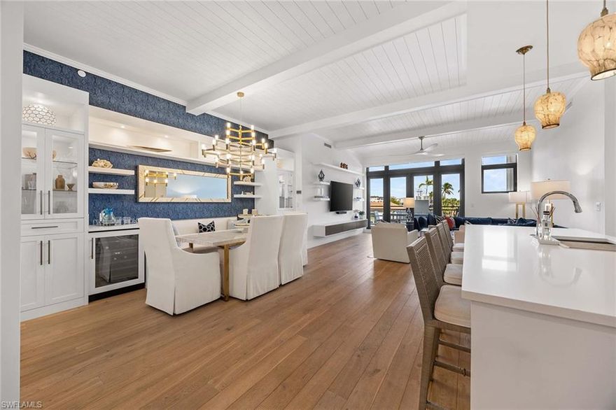 Experience refined coastal living in the heart of downtown Naples, just one building from Fifth Avenue South. Enjoy the rare luxury of two dedicated parking spaces in the secure garage. The living area opens seamlessly to an exceptional 800-square-foot lanai -one of only two residences in the building to offer such an expansive outdoor living space— creating an effortless indoor-outdoor lifestyle.  This sophisticated three-bedroom, three-and-a-half-bath residence offers an open, light-filled floor plan with Legno Bastone hardwood floors throughout. The chef's kitchen features premium Thermador appliances, Arctic white quartz countertops, and a generous center island ideal for entertaining. A custom-built-in banquet anchors the dining area, complemented by a wine refrigerator, dual refrigerator drawers, and bespoke cabinetry for serving and storage. The primary suite is a serene retreat with a custom walk-in closet featuring dual rotating shoe racks and a spa-inspired bath with dual vanities, soaking tub, and spacious walk-in shower. Residents enjoy a rooftop oasis with a pool and hot tub, lounge seating, shaded dining areas, and premium built-in grilling stations. Generator, 2 storage rooms.