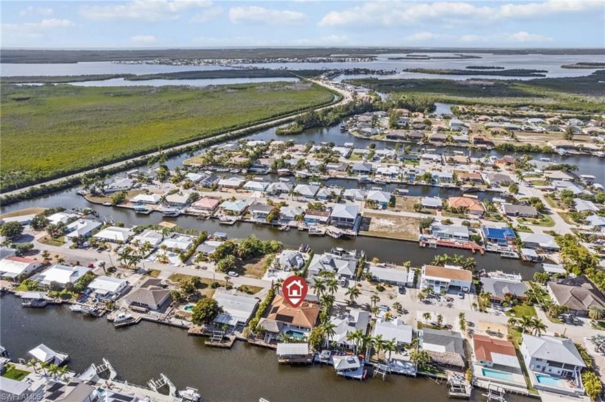 Calling all boaters and island lifestyle buyers. Welcome to a true waterfront island retreat in Matlacha Isles, where no expense was spared in transforming this home into a luxury coastal oasis with fast direct boating access. From your dock, enjoy minutes to renowned Back Bay fishing, Pine Island Sound, barrier islands, sandy beaches, and premier tarpon fishing grounds in the Gulf of America. This home offers almost 2,000 SF of open living space with 3 bedrooms, 2 full bathrooms, and a 2 car garage. A very rare oversized lot provides exceptional outdoor space & privacy. Soaring cathedral ceilings, updated luxury vinyl plank flooring with a driftwood inspired finish, and a modern open floor plan designed for both relaxation and entertaining. The remodeled kitchen in 2022 features quartz countertops, new appliances, and is open to the living & dining areas. Large sliding glass doors frame stunning water views, while an interior dry bar just off the kitchen creates the perfect space for hosting or enjoying island time. The outdoor living area was completely reimagined in 2023 and is nothing short of spectacular. The Pebble Tech finish heated saltwater pool and spa are surrounded by luxury travertine pavers, and a full-size tiki hut with bar and complete outdoor kitchen creates the ultimate setting for entertaining. Picture parties, family gatherings, and evenings with friends, all overlooking the water, surrounded by swaying palms, birds of paradise, and lush tropical landscaping that offers beauty and complete privacy. BOATERS check out the wraparound dock with a 14,000 pound boat lift featuring a custom canopy, along with power, water, and a cleaning station. Open water access is just minutes away. The water is your playground with countless waterfront destinations to explore. This home is built for peace of mind. It remained high and dry during all storms, with a raised stem wall where water never reached the pool. Features include a designer-tile-style metal roof installed in 2019, hurricane-impact windows & doors, and motorized hurricane screens on the rear lanai. Energy-efficient home & Pentair pool pump, heater, and smart controls installed in 2023, all operable from your smartphone. Over the past 4 years, this residence has been extensively renovated, inside and out, using high-quality materials and finishes. Matlacha Isles offers a unique blend of island living and accessibility, positioned between Cape Coral and Pine Island, allowing you to enjoy the waterfront island lifestyle without heavy traffic or isolation. Groceries, shopping, dining, and entertainment are all just minutes away. Enjoy boating to Southwest Florida’s barrier islands, beaches, and waterfront dining. The upcoming Cape Coral Grove, a 131-acre mixed-use town center, will feature upscale retail, dining, hotels, public parks, and community events. Seven Islands will bring restaurants, boutique shops, marina, green spaces, and possibly even a beach area!