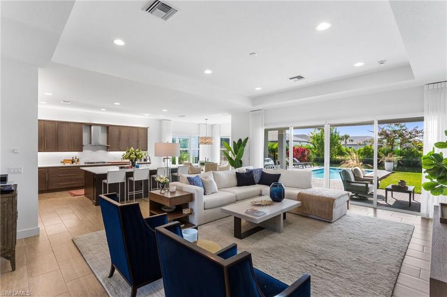 This stunning "Seabreeze" model home offers an unparalleled blend of luxury and comfort in the highly sought-after Valencia Trails, Naples’ premier 55+ community. This thoughtfully designed home provides exceptional flexibility—easily functioning as a three-bedroom layout thanks to a closet in the family/den area, or serving as a private in-law suite with the added benefit of its own dedicated garage. From the moment you step into the 14-foot-ceiling foyer, you feel an immediate sense of sophistication. The open-concept design seamlessly connects the kitchen and living areas, making it ideal for both everyday living and elegant entertaining. The chef’s kitchen is a true showpiece, featuring quartz countertops and backsplash, a natural gas stove, premium stainless steel appliances, and pull-out trash bins. Cabinetry with soft-close functionality and elegant molding adds a touch of refinement, while ample recessed lighting enhances the space. A coffee/wine bar was custom-built with an 88-bottle wine cooler and two pull-out refrigerator drawers. Additional highlights include over $20K in custom window treatments, designer wallpaper, enhanced landscaping, and three full garages. Sliding glass doors lead to a covered lanai overlooking a custom pool, fenced backyard, and an outdoor kitchen with a natural gas grill and pizza oven. The home is equipped with hurricane impact doors and windows for peace of mind. The backyard is fenced in with ample space for outdoor activities. Some of the furniture will be conveyed for convenience.  Beyond your doorstep, Valencia Trails offers world-class amenities that enhance an active, social lifestyle. The impressive 43,000-square-foot clubhouse features a full-service restaurant and bar, a state-of-the-art fitness center, a full-service salon and spa, and multiple recreational spaces, including card rooms, an art studio, and a learning kitchen. For those who love outdoor activities, the community boasts a resort-style pool, a lap pool, a resistance pool, six tennis courts, eight pickleball courts, and scenic walking and biking trails. Even your four-legged companions will feel at home with two dedicated dog parks. This is more than just a home—it’s an opportunity to embrace a luxurious, resort-style lifestyle in one of Naples’ most exclusive communities. Homes like this are rare, and demand for Valencia Trails continues to grow. Don’t miss your chance to own a piece of paradise.