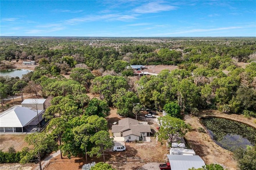 Set on over one acre in a quiet, peaceful setting just minutes from I-75 and Southwest Florida International Airport, this property offers a rare combination of usable land, functional structures, and complete flexibility, with no HOA/restrictions. The property includes two large pole barns/shops and an additional concrete-slabbed shed, providing extensive covered and enclosed space for RVs, boats, trailers, work vehicles, equipment, storage, or workshop use. The layout allows for easy access and maneuverability throughout the acreage, with room to expand or reconfigure as needed. Inside, the home offers a practical, comfortable layout with natural light and functional living spaces designed for everyday use. The home features a newer roof. Mature trees create privacy while maintaining an open, functional footprint that maximizes usable space. Properties offering over an acre, multiple outbuildings, a peaceful setting, and unrestricted use in this convenient corridor location are increasingly rare.