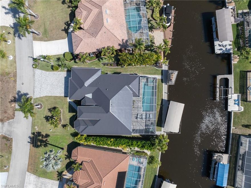 ONE NOT TO MISS! This exceptional 2016 high-luxury-built contemporary Cape Coral Gulf-access Pool and Spa home with quick boating access, offers 2,438 sq ft of beautifully renovated living space and comes "turn-key furnished" and loaded, featuring 3 bedrooms, 3 full bathrooms, an office/den, and a 3-car garage, all enhanced by an open floor plan, high ceilings with dramatic 11-ft high 90-degree Zero/Corner Door pocketing sliders—that seamlessly blend indoor and outdoor living. The totally renovated designer kitchen showcases beautiful stacked glass-front upper cabinets with interior lighting above 42" uppers, quartz countertops, stainless appliances with induction range, pull-outs, wine cooler, icemaker, sea-glass pendant lighting, and a huge long entertaining island bar with Kohler farm sink. A rear dining area views the water. The Master Suite offers sliders to the lanai, a drive-through walk-in shower, a soaking tub, dual stone top vanities, 2 walk-in custom closets, a travertine stone accent wall & elegant chandelier lighting. A private En-Suite Guest bedroom with its own full bath provides ideal guest accommodations, complemented by Fanimation fans, custom window treatments, double-door entry with transom lighting, custom built-ins, and renovated bathrooms. Outdoor living is elevated rear Southern exposure, an oversized saltwater heated pool and spa, full pavers sundeck, newer screened in pool cage with 4 panoramic picture window screens, an outdoor cook center with ventilation, mini bar, outdoor TV, a SuperMax electric hurricane rated roll down screen across the lanai, 2 Outdoor storage closets, a full pool bath and a spacious lanai overlooking the water, all set atop an extended full-length paver pool deck *** View the ZILLOW tour and walk through Vimeo Tour linked  *** with floor plan linked to fully appreciate the exceptional quality and lifestyle this home offers. Now for the Boater, this property offers approximately 94 ft of seawall with a Captain’s walk, 10,000-lb boat lift with canopy, extended 94 ft composite decking, a Tiki hut, and a waterside sundeck. Some of the many features and upgrades in this home include a 2023 standing seam metal roof $96,250., rain gutters around home, soffit lighting, impact hurricane windows and doors, Custom Interior Wide Slat Bahama Shutters, Security Sys, Interlink security cameras, a 71" big-screen TV w/sound system, paver driveway and walkways, and meticulously manicured landscaping. Perfectly situated close to everything yet tucked away in a little-known upscale neighborhood of fine estate homes, this property sits between Del Prado and the river, quick access to the Caloosahatchee Waterway accessing the Gulf and Beaches. Located near a 365-acre Four Mile Cove Ecological Preserve with its scenic hiking trails. This impectable home is an exceptional rare find and truly shows like new construction. NO HOA Fees. This home did not have any flood damage from Hurricane Ian. We welcome buyers & agents!