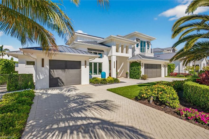 Just steps from the Gulf, this exceptional coastal contemporary residence offers the perfect blend of refined style and relaxed Naples living. Designed through the collaboration of Integral Builders, Lotus Architecture, and L1 Design, this two-story masterpiece spans over 4,100 square feet of sophisticated living space.

A grand entry introduces the home’s light-filled interior, where soaring 22-foot ceilings and expansive glass walls create an effortless indoor-outdoor flow. The open-concept design centers around a dramatic great room with a striking feature wall and fireplace, seamlessly connected to a dining area and an elegant chef’s kitchen. Outfitted with Wolf and Sub-Zero appliances, an impressive waterfall-edge island, and a spacious walk-in pantry, the kitchen combines beauty and function in perfect harmony.

The first floor features two serene bedroom suites, including a luxurious primary suite with shiplap ceiling detail, a spa-like bath, dual closets, and private access to a sunlit terrace. A dedicated study with sliding barn doors provides an ideal work-from-home retreat. Upstairs, guests are treated to two additional en suite bedrooms, a comfortable loft lounge, and a balcony overlooking the pool.

Outdoors, the home’s resort-inspired design continues with a covered lanai, outdoor fireplace, full summer kitchen, and a sparkling pool and spa—an entertainer’s dream. Completing the property is a 4 bay garage, ideal for car enthusiasts or extra storage.

Originally crafted as a model residence, this home showcases elevated design elements and thoughtful architectural details throughout—a stunning statement of coastal luxury just two blocks from the beach.