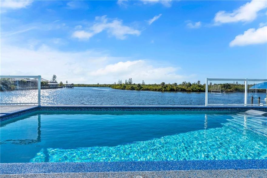 Experience the pinnacle of modern coastal luxury in this custom-built 2025 waterfront masterpiece with direct sailboat access to the Gulf. Thoughtfully designed for innovation, comfort, and elevated entertaining, this exceptional residence offers 3,784 square feet of impeccably crafted living space. The home features 3 oversized bedrooms, a private office, a dedicated theater/flex room with bar, and 4.5 beautifully appointed bathrooms. Each spacious bedroom includes its own en-suite bath, ensuring privacy and comfort for family and guests. One guest suite is uniquely appointed with a private washer and dryer, creating an ideal retreat for extended stays or multigenerational living. At the heart of the home, the show-stopping chef’s kitchen is designed to impress. Complete with a pot filler at the stovetop, two expansive waterfall-edge islands with seating for eight, and a walk-in butler’s pantry featuring a second dishwasher, this space is perfectly suited for effortless entertaining and everyday living. Motion-activated kick lighting in the kitchen and primary bath adds a sleek designer touch, while dimmable lighting throughout allows you to create the perfect ambiance in every room. Built for both durability and efficiency, the home is equipped with hurricane impact windows and doors, Icynene spray foam insulation for superior climate control and sound reduction, a whole-home reverse osmosis system, and a Fuji septic system for long-term reliability. The entire residence is wired for CO-AX and HDMI, ensuring seamless entertainment integration throughout. Even pets are considered, with a custom dog room featuring foil-lined walls for durability and easy maintenance.
Outdoor living is equally exceptional. Dual-system retractable screens and hurricane screens provide flexibility and protection, while mini-split systems in both the garage and lanai ensure year-round comfort. A built-in bug misting system enhances outdoor enjoyment. The lanai and pool area showcase premium FloCo rubber flooring — a 15+ year, slip-resistant, cool-to-the-touch, low-maintenance surface that resists cracking and delivers superior durability and comfort compared to traditional finishes. Car enthusiasts and adventure seekers will appreciate the impressive 1,200+ square foot air-conditioned garage featuring soaring 17-foot ceilings and a garage door that opens directly to the back lanai — creating seamless indoor-outdoor functionality and incredible versatility for entertaining, storage, or showcasing your collection. An expansive RV garage provides even more flexibility to accommodate a boat, RV, or additional vehicles — the ultimate complement to a waterfront lifestyle. Every detail reflects superior craftsmanship, forward-thinking technology, and refined design — a rare opportunity to own a newly constructed luxury home built without compromise.