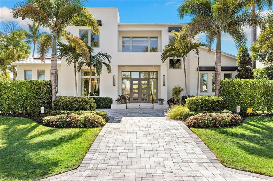 Welcome to this striking coastal contemporary residence in the heart of Naples, built in 2021 and offered fully furnished. Designed by renowned interior designer Jeffery Fischer, this light-filled two-story home blends refined architecture, elevated design, and seamless indoor-outdoor living. Privately set behind lush tropical landscaping, the property lives like a quiet, serene compound - offering remarkable privacy and tranquility while just blocks from 5th Avenue South dining and shopping, the Gulf's white sand beaches and the new Four Seasons Hotel.  A dramatic entry opens to soaring ceilings, wide-plank wood flooring, and an impressive open staircase with gallery overlook. The thoughtfully designed floor plan offers approximately 3,290 square feet of living area, featuring four bedrooms, three full baths, a powder bath, and a dedicated pool bath. The private primary suite overlooks the tranquil pool and spa, creating a peaceful retreat filled with natural light. The chef's kitchen is both stunning and functional, featuring Thermador appliances and a Miele built-in coffee system, and highlighted by a large waterfall island, custom cabinetry, statement backsplash, and a gas range supplied by propane. The main living area opens effortlessly to the outdoor lounge and covered lanai, creating a true indoor-outdoor lifestyle ideal for entertaining.