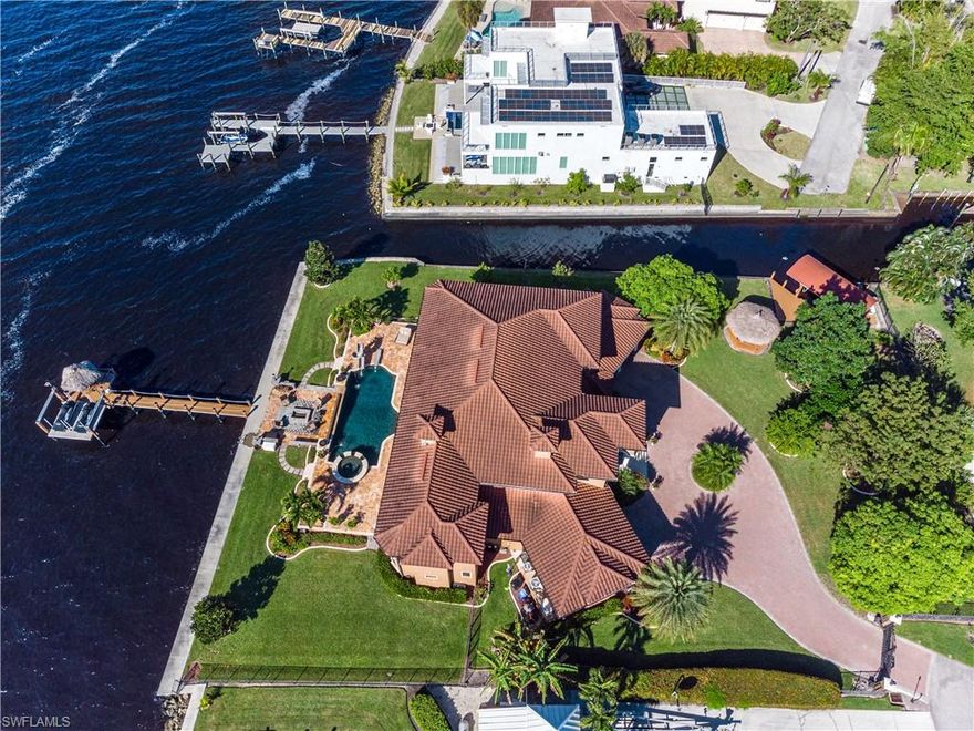 One of Fort Myers finest waterfront properties! This rarest type of specimen location measures 0.8 acre fronting both the Caloosahatchee River and navigable canal. 367 linear ft of seawall with 150ft captains walk along the river. Nearly new custom luxury home by legendary builder Norm Bloxham exceeds 8,450sf under roof. Ground level master has palatial closet, shower body jets, two person jetted stereo tub, heated towel bar. 2nd master up, 3rd suite up, 4th suite adjacent to office, great room, dining room, theater, fitness loft, 2 half baths, and 2 double garages. Features include gated entry, cameras, impact windows, 2 generators, 1000gal LP tank, fireplace, marble, granite, cherry, gas cooktop, Subzero, wine refrigerator, laundry chute, pantry, water purification, steam shower. Exterior includes fenced yard, circle drive, river dock, 2 PWC lift, canal dock, 10k lb covered boat lift, gazebo, outdoor kitchen, pizza oven, 9ft deep infinity edge pool, diving board, slide, lighted Laminar flows, party spa, travertine pool deck, fire pit, mosquito mister. Avocado, mango, jack fruit, sugar apple, and lychee trees. Study the photos, watch the video, and schedule an hour to preview!