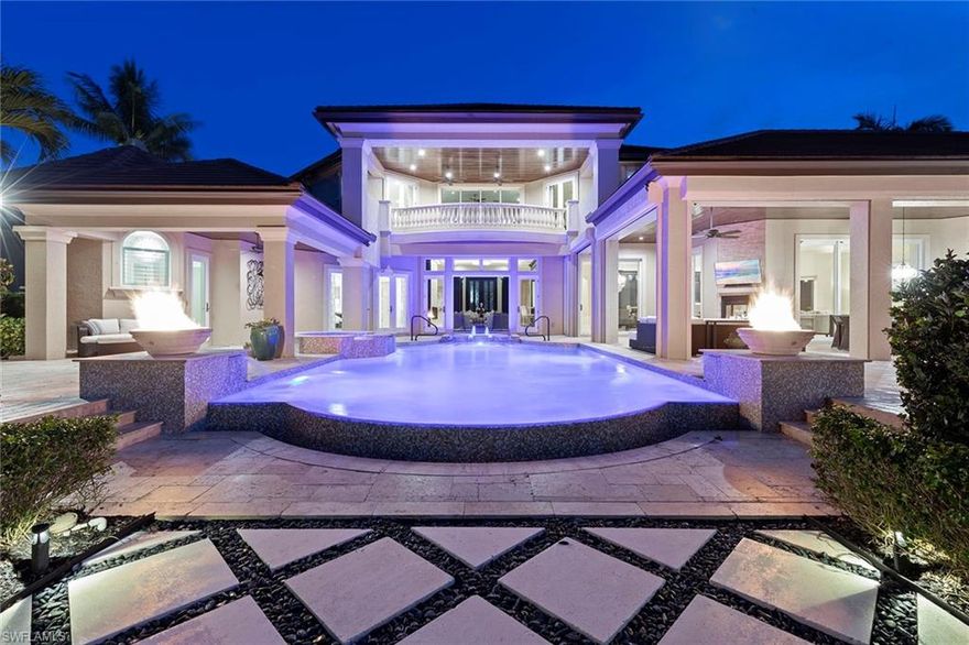 Behind the gates of Bay Laurel Estates, a highly sought-after enclave within Pelican Marsh secured by two manned entries, 8732 Purslane Drive offers a rare blend of elegance and sophistication. Poised on nearly half an acre, the residence features five bedrooms, a den and five and a half baths across 6,650 sprawling square feet of living space. Soaring ceilings and custom finishes create a sense of grandeur, while multiple fireplaces and refined details add warmth. The chef's kitchen, outfitted with Wolf appliances, a butler's pantry and an oversized island, opens to the stunning living and dining areas. Entertaining is effortless with a climate-controlled wine room, illuminated bar and private fitness studio. Outdoors, the resort-style lanai includes a summer kitchen, fireplace, fire pit and electric screens. Surrounded by lush landscaping, a pergola-shaded lounge frames the pool and spa for privacy and relaxation. With a three-car garage, screens and shutters for hurricane protection, and Pelican Marsh amenities including golf, tennis and dining, this residence captures the essence of Naples living.