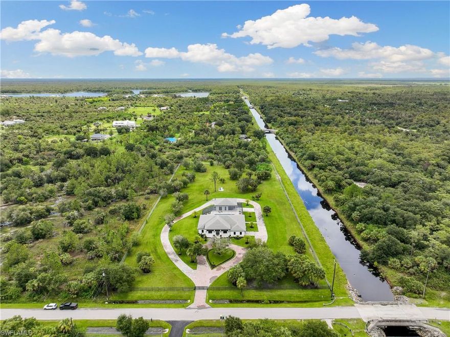Charming & private 5 bed(2 masters w/walk-in closets), courtyard style pool home with an amazing screened lanai with a huge deck, heated oversized pool w/jacuzzi, 2 outdoor kitchens and plenty of entertainment space! This home includes a pool house and an under-air 4 car garage in which cars may be stacked! All this sits on 5 acres of land and on a canal where only the beautiful palms and trees were left. The property is fully fenced! The modern style construction has an open space design, high ceilings with 4 tray ceilings, level 5 granite countertops and level 5 drywall finish. Full house LED lights and full 36x36 tile floors. Spray foam insulation, impact windows & doors, full house RO system, 3 16 seer A/C units, flat tile roof, gutters all around, 500-gal propane tank, paver driveway that surrounds the entire house and an outdoor fire pit. Home also includes surveillance cameras for extra security and comfort. Being conveniently located ~7 min from schools, ~6 min from Publix, CVS & Mobile ONE, and being able to reach Immokalee RD in ~3 min this location is among the most coveted in the Golden Gate Estates. This home is a must see, as it presents all kinds of opportunities!