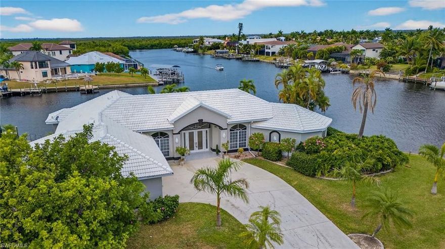 Recently remodeled sailboat-access pool home offering breathtaking intersecting canal views on an oversized lot with 215 feet of water frontage in a prime Southwest Cape Coral location. The stunning chef’s kitchen features a double island with quartz countertops, a spacious breakfast bar seating four, new GE appliances, custom black cabinetry with elegant gold hardware, and panoramic views of the pool and canal.

Soaring vaulted ceilings enhance the kitchen and living room, which also includes a fireplace and wet bar with butcher block countertop and built-in wine cooler—perfect for entertaining. New luxury vinyl plank flooring, updated baseboards, and fresh interior paint complete the modern feel throughout.

Just off the kitchen, the formal dining room offers flexibility and could easily serve as a game room, office, media room, or fifth bedroom. A formal living area welcomes you through new impact-resistant double front doors, while triple sliding glass doors provide seamless access to the screened lanai.

The oversized primary suite is light and bright, featuring a tray ceiling, sliders to the pool and lanai, and a sitting area ideal for enjoying spectacular western sunsets. The spa-like ensuite bath has been beautifully updated with new flooring, tile, vanities, fixtures, and a rainfall shower head. Ample storage includes two walk-in closets and a linen closet.

The fourth bedroom is currently staged as an office and would make an excellent bunk room. Two additional spacious guest bedrooms are split from the primary suite and share a fully updated bath with new tile, flooring, and fixtures. Two half baths add convenience—one serving the main living area and another functioning as a pool bath.

Relax poolside while watching boats pass along the intersecting canals, or enjoy sunset dinners prepared on the brand-new built-in outdoor grill. Just steps away is your private composite dock and lift, with quick access to Cape Harbour and the Gulf via the Spreader Canal.

Additional highlights include a three-car garage, whole-house plumbing repipe, updated electrical panel, new roof (2024), HVAC (2020), and a newer picture-window pool cage. Truly move-in ready—nothing to do but enjoy.

Furnishings shown are available for purchase directly from the staging company. Ideal as a primary residence, second home, or short-term rental opportunity.

Call to schedule your private showing today!