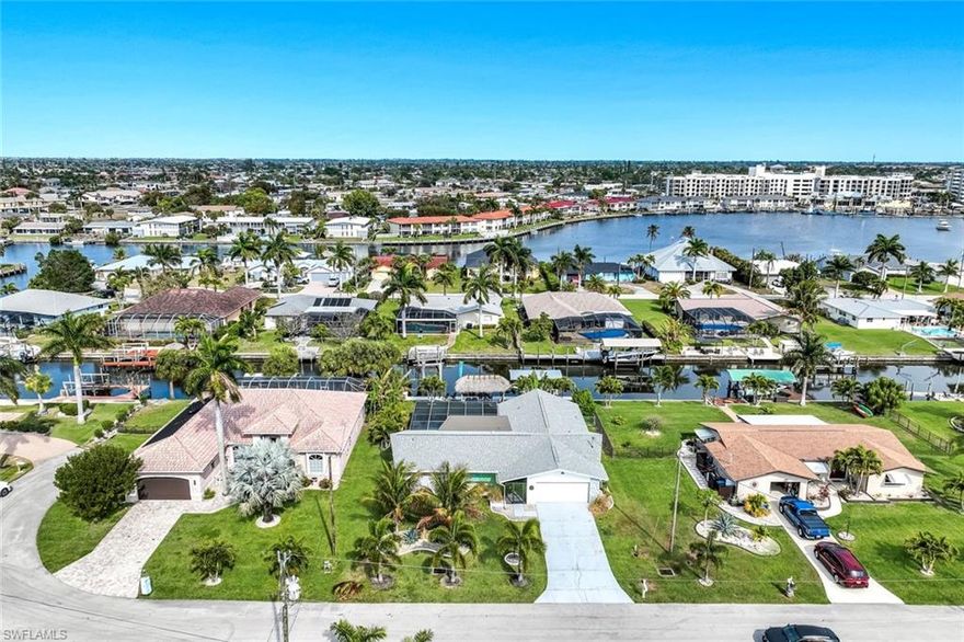 Completely remodeled sailboat access pool home on a deep-water canal just minutes to open water! Ideally located one canal from the Bimini Basin with future boatable access to the highly anticipated Bimini Basin Project and within biking distance to the Cape Coral Yacht Club, this property is truly a boater’s paradise in the heart of Cape Coral! Offering just under 2,000 square feet of living space, this home features 4 bedrooms, 3 full bathrooms, and a two-car garage. Inside, a bright open split floor plan showcases tile flooring throughout. The updated kitchen is beautifully appointed with white shaker cabinetry, quartz countertops with a matching backsplash, under-cabinet lighting, soft-close drawers, stainless steel appliances, and a breakfast bar with a two-drawer mini refrigerator. Designed for entertaining, the custom bar area features quartz countertops, open wood shelving, a built-in beverage refrigerator, and seating overlooking the canal and pool, creating a seamless indoor-outdoor flow. The owner’s suite offers sliding glass doors to the outdoor living area, a walk-in closet with decorative glass doors, and a remodeled ensuite bath complete with heated mirrors, quartz countertops, rain shower head, and a walk-in tiled shower. The two additional bathrooms have also been beautifully updated with modern finishes and custom fixtures, each featuring rain shower heads. Major upgrades provide peace of mind, including a brand-new roof, hurricane impact windows, new plumbing throughout (all completed in 2024), along with a new electrical panel, updated recessed lighting and fixtures, an ADT security system, and split A/C units in both the garage and primary bedroom. Step outside to the expansive screened lanai, offering generous space for outdoor dining, a large heated pool, tiled deck, and a pool bathroom. Boaters will appreciate the brand-new composite dock with a 10,000-pound boat lift (2023) and newly installed tiki hut (2024) with full electrical service. With only a 10-minute ride to open water, this property delivers exceptional boating access. Surrounded by lush tropical landscaping, fruit trees, and a fenced-in backyard, the outdoor space offers both beauty and privacy. Centrally located near Downtown Cape Coral, Cape Harbour, and Tarpon Point, with convenient access to Sanibel, Captiva, Fort Myers Beach, shopping, dining, medical facilities, and top-rated schools, this home embodies the very best of Southwest Florida waterfront living. Schedule your private showing today!