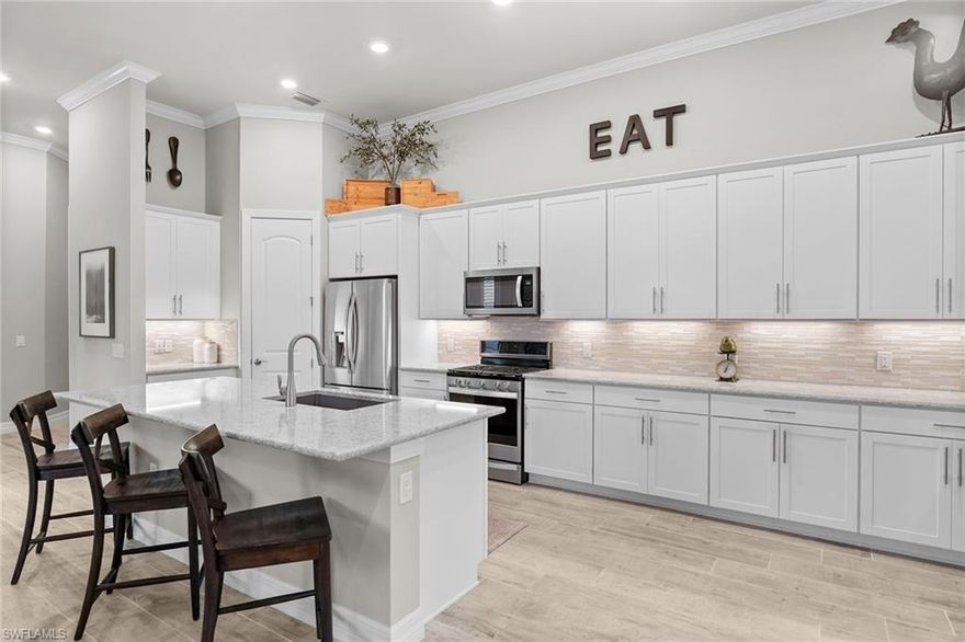 One or more photo(s) has been virtually staged, AI generated or rendered.  Beautifully maintained lakefront residence in the gated community of Avery Square, ideally located in the heart of North Naples just minutes from Vanderbilt Beach, Mercato, Waterside Shops, dining, shopping, and everyday conveniences. Built in 2018 and featuring impact windows and sliders, this newer-construction home offers the benefit of more modern building standards and a well-positioned design for Southwest Florida living.  This 3-bedroom plus den, 2-bath home offers an inviting open floor plan with tall ceilings, tray ceiling details, abundant natural light, plantation shutters throughout, and serene western lake views. The spacious kitchen is designed for both function and gathering, featuring a large center island with sink, gas cooktop, stainless steel appliances, decorative tile backsplash, under-cabinet lighting, generous cabinetry, a walk-in pantry, and room for casual dining. The main living area opens to the covered lanai through sliding glass doors with custom automatic blinds, creating an easy indoor-outdoor flow overlooking the lake.  The primary suite offers a bright and comfortable retreat with tray ceiling detail, custom automatic blinds on the windows, dual-sink vanity with granite countertops, and an oversized walk-in shower with decorative tile and built-in bench seating. Two guest bedrooms are thoughtfully positioned near the guest bath, while the den provides flexible space for a home office, media room, or additional sitting area.  Outdoor living is enhanced by a covered lanai, upgraded brick paver sundeck, expansive backyard green space, peaceful lake views, abundant wildlife, and desirable western exposure for beautiful Naples sunsets. Avery Square offers a secure gated entry, a luxury community entrance framed by royal palms, and a lakefront community park, all in a prime North Naples location just minutes from Vanderbilt Beach, Mercato, Waterside Shops, dining, shopping, and the best of the Naples lifestyle. Everyday conveniences are exceptionally close, with Publix and Food & Thought 2 right next door, plus Whole Foods, Trader Joe’s, and Costco all just around the corner.