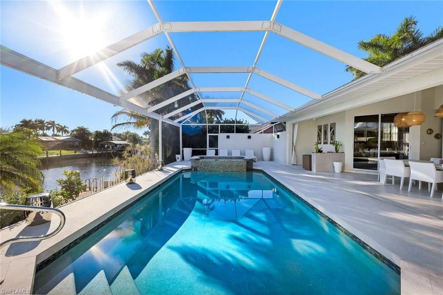 Experience elevated waterfront living in this beautifully updated 4-bedroom, 3-bath residence offering 2,868 sq ft of living space, set on a wide, direct Gulf-access canal with no bridges in one of Southwest Cape Coral’s most desirable boating neighborhoods.

From the moment you arrive, the home makes a strong first impression with mature palm trees lining the front of the property, creating an inviting and distinctly Florida curb appeal. Upon entry, the home continues to impress with its open, airy design, highlighted by vaulted ceilings, clear sightlines through the living space, and pocketing patio sliding glass doors that fully open to the lanai—creating a seamless indoor-outdoor connection. Tile flooring throughout, clean modern finishes, and impact windows enhance both style and comfort.

The open-concept kitchen is designed for everyday living and entertaining, featuring Quartz countertops, custom cabinetry, stainless steel appliances, wall ovens, a walk-in pantry, and generous island seating. The kitchen flows effortlessly into the main living and dining areas, all oriented toward the outdoor living space and water views.
The spacious primary suite offers tranquil pool and canal views, dual walk-in closets, and a spa-inspired bath complete with a freestanding soaking tub, oversized walk-in shower, and dual-sink vanity. Guest bedrooms and baths are thoughtfully designed, and the home also includes a dedicated office, ideal for remote work or flexible use.

Outdoor living is exceptional. The expansive screened lanai serves as a private retreat featuring shell stone decking, upgraded lighting, a saltwater pool with entry steps and built-in bench seating, and a raised spillover spa—perfect for relaxing or entertaining year-round. Boating enthusiasts will appreciate the oversized dock with boat and jet ski lifts, offering effortless access to open water.

Additional highlights include a 3-car garage (2-car + 1-car) with epoxy flooring and storage, an updated laundry room with cabinetry, and a prime location near Cape Harbour Marina, waterfront dining, and shopping.