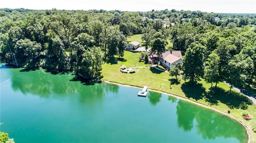 Spectacular Big Cedar Lodge inspired ranch sitting on 6 acres with over 5300 sf of living space features an open floor plan enhanced by handscraped hardwood floors and timber beams! Inviting entry foyer leads to generously sized dining room & stunning great room with cathedral ceiling, floor-to-ceiling stone fireplace & wall of windows overlooking private lake & impeccably landscaped grounds.  Designer kitchen with soapstone countertops, 42” cabinetry, premium appliances & 8’ x 5’ center island adjoins light-filled breakfast room & vaulted gathering room.  Spacious master bedroom suite features walk-in closet, luxury bath & atrium door to deck. 3 Generous-sized additional bedrooms, 2 full baths & upper level bonus/bed room complete the living quarters. Walk-out Lower Level includes recreation room, family room with stone fireplace, 2nd kitchen & full bath. Tucked away on 6+ scenic acres with an acre stocked lake, deck with wet bar & fireplace, patio with firepit and 2 & 4-car garages.