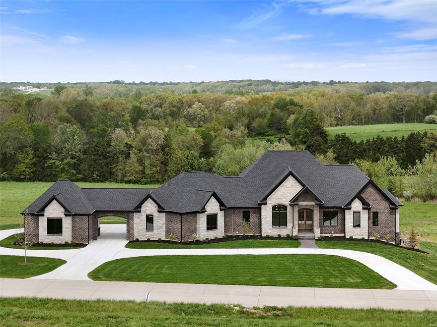 Welcome to this stunning new construction luxury home on 5+/- acres near Wentzville, MO, blending modern architecture and design. This home features clean lines, natural materials (wood, stone, brick), and expansive windows that flood the space with light. The open floor plan includes 10' ceilings, a gourmet kitchen with quartz countertops, oversized island, commercial-grade appliances, and custom cabinetry. Enjoy engineered hardwood floors, gas fireplace, dedicated office/study, and a large walk-in pantry with a counter and shelving. Outdoor living shines with a suspended stamped concrete patio, irrigated yard, and fresh landscaping. A porte-cochere connects to an extra 2-car garage, offering 4 total spaces. Sophisticated, spacious, and serene—this home has it all. Additional Rooms: Mud Room