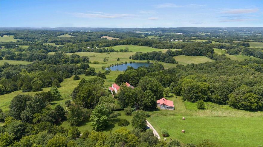 Located just minutes from downtown Hermann, this enchanting country estate rests atop 47+/- sprawling acres! The site is curated with delightful garden paths that lead to a charming farmhouse, a barn, a greenhouse, a potting shed, a 2-acre lake and a spring-fed pond. The farmhouse was redesigned in 2000, preserving its historic log structure while evolving into modern living. The first floor is perfect for formal and intimate gatherings with a chef’s kitchen, a windowed great room, a dining room, a breakfast room, an office, and a primary suite, all wrapped with covered porches to take in awe-inspiring views. Upstairs are two additional bedrooms and a full bathroom. The lower level features an open recreation/dining area, kitchen, additional bedroom, full bathroom, and a private entrance. This setup is perfect for large families, guest privacy, or a separate rentable space. The property was designed as a cut-flower farm but the possibilities are endless! Additional Rooms: Mud Room