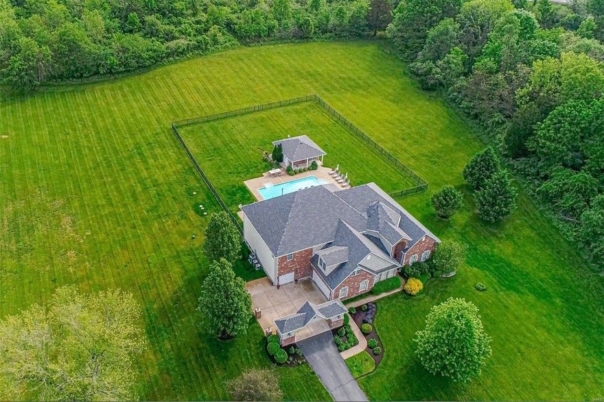 This stunning 1.5-story estate is beautifully appointed on over 9 level acres. Open and airy floor plan with impressive office, formal dining, bright great room with soaring ceilings, a sprawling eat-in kitchen with breakfast bar, and large hearth room with stone fireplace. The main-floor primary bedroom suite boasts a newly renovated primary bath and a sitting room with a fireplace that walks out to the beautiful pool area. Upstairs boasts three large en suite bedrooms, a bonus room, and a loft area. Outside offers a large fenced-in area with an in-ground pool, BBQ area with countertop space, and a pool house with a sitting room, bar, and full bath. Towards the back of the property is more flat acreage that leads to a well-manicured wooded area with wide walking/riding trails. Bring your horses, toys and have a ton of fun on this extremely rare opportunity.