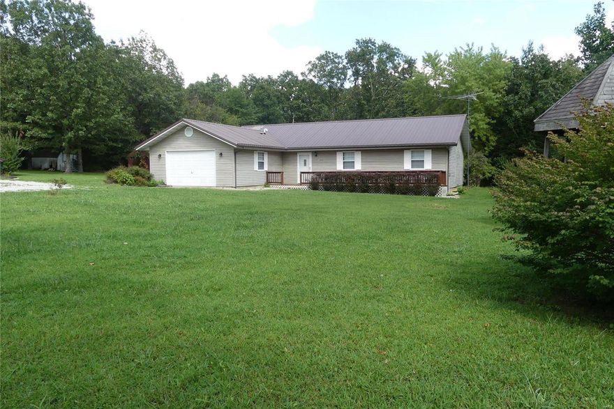 This three bedroom two bath home nestled against a wooded background sits on 4 acres located between Raymondville & Yukon.  The spacious living room with patio doors that open up to the back yard joins the kitchen and dining room.  The kitchen has room for a breakfast table and has lots of storage in the custom cabinets and pantry.  An extra wide hallway leads you to the 3 spacious bedrooms including a master suite with a full bath and walk in closet.  Watch the sun set over the beautiful front lawn from the full length front deck.  Private well and septic.  Equipped with a propane and a wood furnace for central heat.  The seller has taken good care of this home and there are other nice features that make it a very comfortable place to call home!