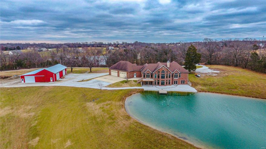 NO CITY RESTRICTIONS~NO HOA~UNINCORPORATED ST. CHARLES COUNTY~ZONED AGRICULTURAL Custom atrium ranch on 8.14 acres overlooks a deep and stocked pond, which also serves as the source of its dual commercial grade geothermal units. Custom features include 8 ft. solid interior doors, masonry fireplace, spacious gourmet kitchen w/stainless appliances, granite countertops, an expansive island, walk-in pantry, wall mount double ovens, wet bar and custom cabinets. The adjoining breakfast room has coffered ceilings with hidden lighting and a private deck, perfect for enjoying the deer and turkey. The primary bedroom suite, second and nonconforming third bedroom (office) are spacious and located on the main level; two additional en suite bedrooms with custom walk in closets are in the finished lower level. Walk-out lower level is perfect for entertaining, with masonry wood burning fireplace, wet bar ready plumbing, storage and a vintage bank vault door! Did I mention no HOA or city restrictions? Additional Rooms: Mud Room