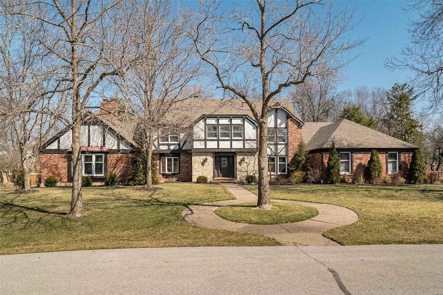 A rich blend of brick, stone & stucco highlights the remarkable curb appeal of this spectacular 1.5-sty Tudor in prestigious Strathmore. 2-Sty hardwood foyer opens to formal dining room, living room with marble fireplace & spacious family room with beamed ceiling, floor-to-ceiling brick fireplace & built-in bookcases. Exceptionally large kitchen with 42” white cabinetry, granite countertops, stainless steel appliances & 7’ center island adjoins light-filled breakfast room with wide bay window. Galley hallway leads to sumptuous master bedroom suite with architectural columns, sitting area with bookcase & fireplace, luxury bath with freestanding tub & French doors that open to private deck. Split staircase accesses 4 additional bedrooms, 1 with ensuite bath, & hall full bath. Lower Level entertainment space includes recreation room with 4th fireplace & wet bar, game room, office, workout room & pool bath. Situated on a 1-acre cul-de-sac lot with deck, patio, pool, hot tub & 4-car garage.