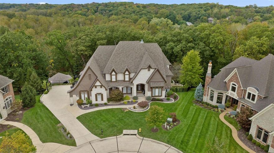 Nestled at the end of a serene cul-de-sac, sits a once-in-a-lifetime opportunity! 6,910sqft of finished area awaits. Greeted by a grand 2-story foyer & great room w/ wet bar & cozy fireplace. Wall-to-wall windows offer breathtaking views of lush trees & sunsets. The heart of the home is the designer kitchen w/ granite counters, Wolf appliances, butler’s pantry & 14' island. Overlooking a cozy hearth room w/ timber-beamed ceiling & stone fireplace.  Retreat to the coffered master suite, featuring an enormous 31' x 13' walk-in closet & a spa-like luxury bath. Two staircases lead to the second floor w/ 3 more bedrooms & 2 full baths. The walk-out lower level is an entertainer's paradise, featuring a family room w/ a fireplace, wet bar, built-in bookcases, media room, 5th bedroom or office, &  full bath. Outside, the magic continues w/ an infinity pool, hot tub, fire pit, composite deck, pool gazebo w/ spacious bar & outdoor kitchen. This extraordinary home is a true gem!