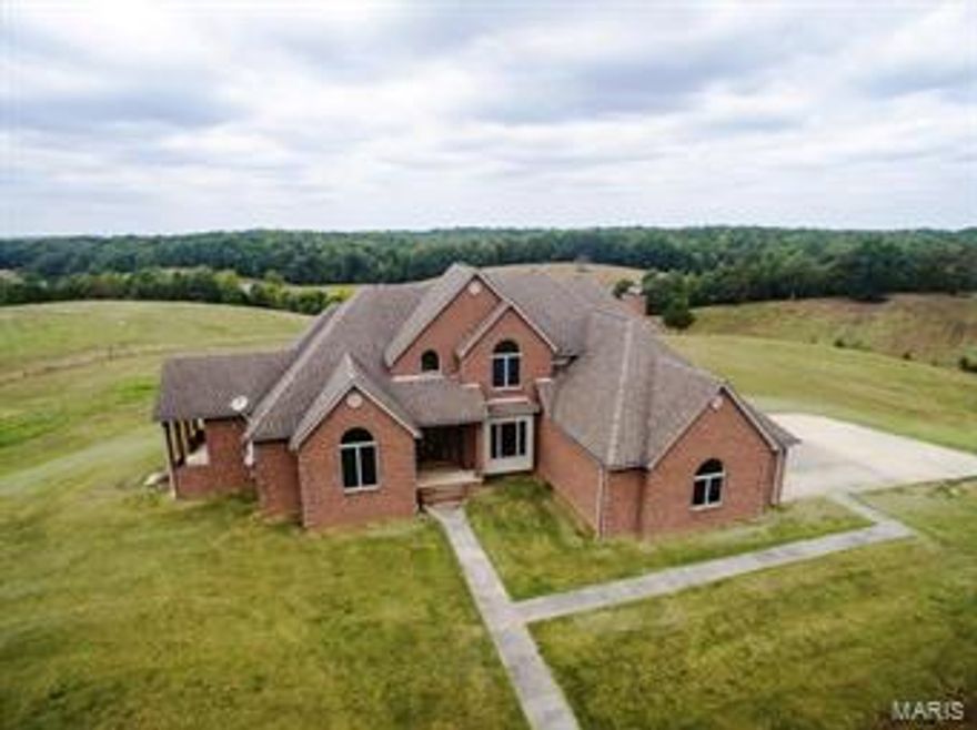 65 Angus Lane, Poplar Bluff MO - Located just Northeast of Poplar Bluff on NN Highway in Butler County, this large custom design/build is neatly situated on a beautiful 130 acre +/- rolling livestock farm with State conservation lands on either side. Improved pasture has been fenced and cross-fenced with half a dozen ponds, working pens, equipment sheds and hay barns. The 6 bedroom 4.5 bath brick home is well finished with countless custom touches including.