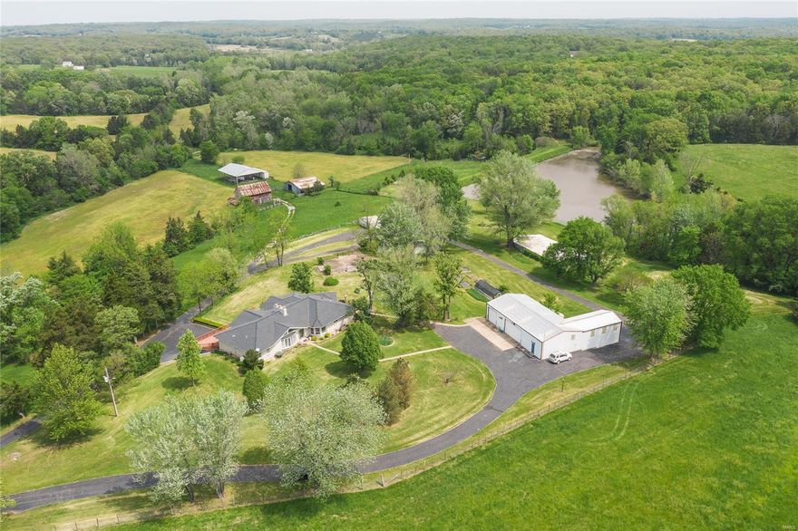 Made of marble from Batesville, Arkansas this home is custom and every detail is exceptionally well done. The home overlooks stocked lake as well as pastures & stunning views. The 150 acres of land is approximately 80 acres wooded with some marketable timber and the rest in row crops and hay fields. Opossum Creek meanders through the property, along with several springs.  Multiple outbuildings including 5 bay workshop (one with car lift & loading dock), several pole barns, large hay barn, concrete bbq patio/outdoor kitchen with storage under, chicken coop/dog pen, greenhouse with raised beds, gazebo, deer stand. The home has a geothermal system, Generac whole house backup system, heatilator wood burning fireplace making it very efficient, accessible features including stair chairlift, wide doors & some bathroom upgrades. Other home features to note, hot tub room, large master suite, walk-in closets & full walkout finished basement. Less than hour from St Louis to your country paradise! Some Accessible Features