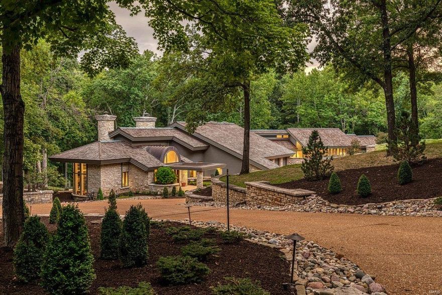 Magnificent Frank Lloyd Wright-inspired ranch w/ over 9900 sf of living space. 14’ floor-to-ceiling windows provide intimate views of the natural surroundings while handscraped hardwood flooring, dimensional ceilings & curved walls add to the home’s graceful ambiance. Dramatic barrel-vaulted foyer leads to private study with custom built-ins, dining room with domed ceiling & great room with beamed vaulted ceiling & full-height stone fireplace. State-of-the-art kitchen featuring custom cabinetry, granite countertops & commercial grade appliances adjoins gathering room with wet bar. The master bedroom suite is a haven of luxury with fireplace, 26’x11’ customized closet & beautifully appointed marble bath. Spectacular galley hallway leads to 2 additional bedrooms (one with ensuite bath), hearth room & 2nd kitchen. Lower Level includes recreation room, game room & full bath. Tucked away in a perfect location adjacent to 60 acres of secluded woods w/ private terraces, pool & 4-car garage.