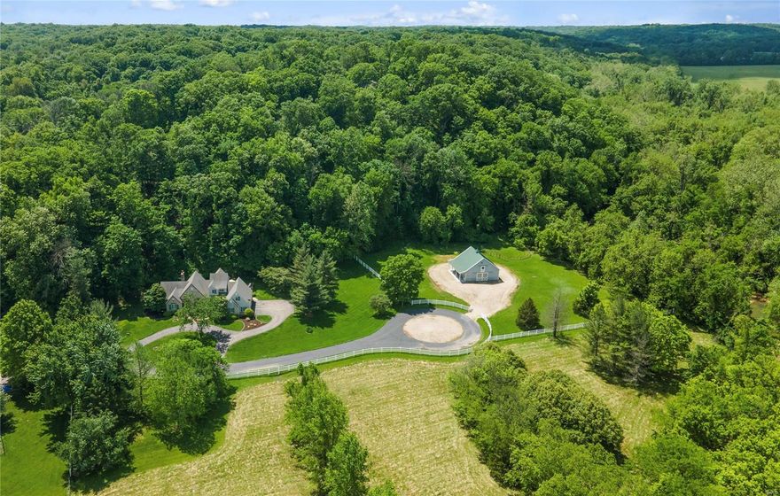 Step into the pages of a storybook with this French-inspired equestrian estate on 6.7+ acres in Wildwood! The property boasts a 4-stall barn, riding ring, and pasture. The residence designed by Dick Busch exudes privacy and abundant natural light throughout. The great room's towering stone fireplace and expansive windows integrate into the natural landscape, framing its wooded surroundings and flowing into an elegant dining room for formal gatherings. The custom kitchen incorporates breakfast and family rooms, which open onto a stone patio. Retreat to the main floor primary suite, a luxurious escape with vaulted ceilings and a spa-inspired bathroom. Upstairs are two bedrooms, a recreation room, and a full bathroom. A finished lower level adds additional recreation areas. Outdoors, a country oasis with open patios and sprawling spaces offers a peaceful respite...your private sanctuary awaits! Additional Rooms: Mud Room