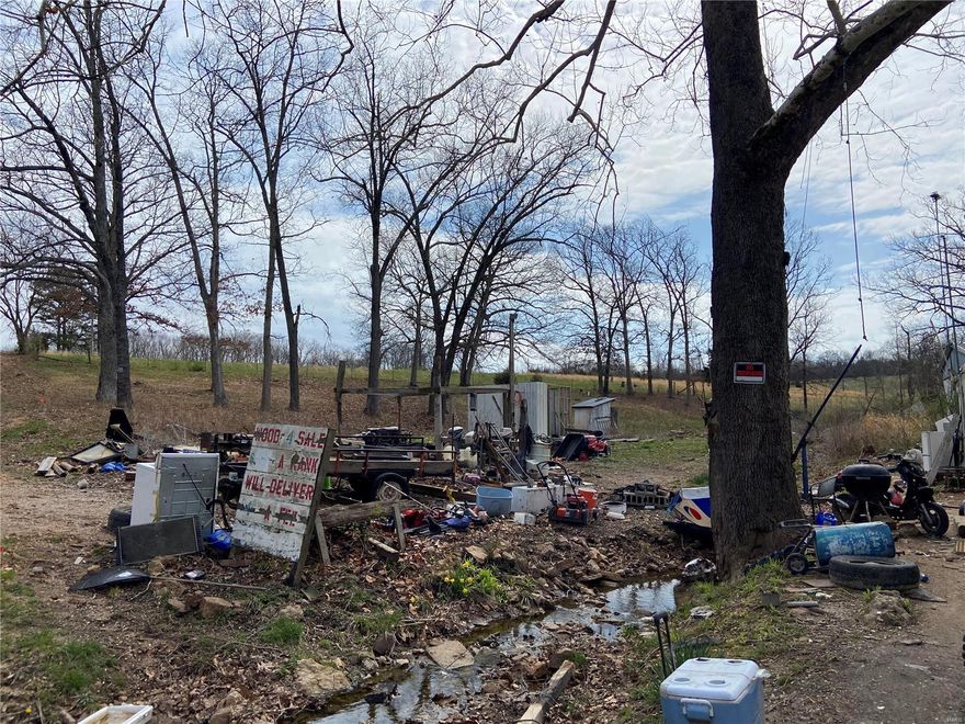 L854 - This 1.2 acre parcel is currently being rented by a tenant at $175 a month, with a month to month tenancy.  There are several trailers and vehicles and much miscellaneous debris all through out the property, all of which is owned 100% by the tenant and in theory would not go with the property.  The tenant wishes to stay, so with a nominal amount down the monthly rent could cover mortgage payments and purchase the property for you.  There is a well (may need to be serviced) and a septic system on the property, as well as electric.  There is also a wet weather creek that could be expanded.  Drive by's only on this unless there is definite interest as nothing on the property is included with the sale.  There is a fence around the sides and the back of the property which will give a good indication of the size. Additional Rooms: Other