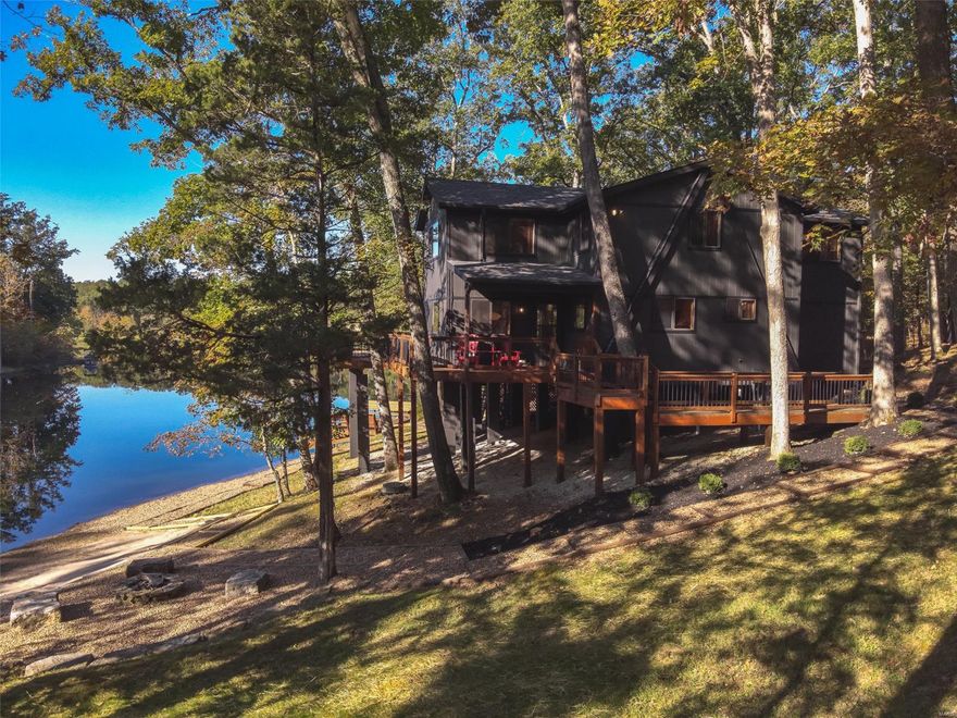 This stunning, fully furnished 4 bed and 2 bath lakefront chalet offers the perfect getaway. Set on a serene 20-acre lake and boasting a private lakeside dock, sandy beach, and cozy firepit for those relaxing evenings by the water. In September, the exterior was refreshed with a new roof and fresh paint, ensuring it’s in pristine condition. A storm shelter adds safety, while the large storage shed with electricity provides ample space for storing a golf cart or other gear. Inside, the vaulted great room showcases breathtaking views of the lake and surrounding forest, creating an inviting and peaceful atmosphere. The kitchen (with newly installed granite counters and appliances) features an oversized breakfast bar. The four spacious bedrooms provide plenty of room for family and guests. Entertain inside or out with room for any sized crowd! Ready to move in, this lakefront retreat offers the ultimate blend of comfort and outdoor adventure, waiting just for you!