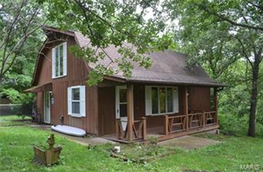 A little piece of heaven in the woods.  Neat and unique 2 bedroom, 2 bath home awaits you at the end of a circular drive backing up to woods.  Main floor includes remodeled kitchen with all stainless steel appliances, tile floors that flow from dining area though to kitchen.  There is a pantry, guest bedroom or office, a bath with shower and storage space.  The living room has a featured stone fireplace, barn wood wall and impressive stone half way up the walls.  Some furniture will stay.  Upstairs is the master bedroom with step out balcony, walk in closet, skylights, a jetted tub, and convenient washer dryer tucked in the bathroom.  Since 2016 Owner has added new electric panel, PEX plumbing, flooring in the living room, a high efficiency Pellet/Corn wood burning stove, and fencing.  Close to an arm of the Mark Twain Lake.  Make your appointment.