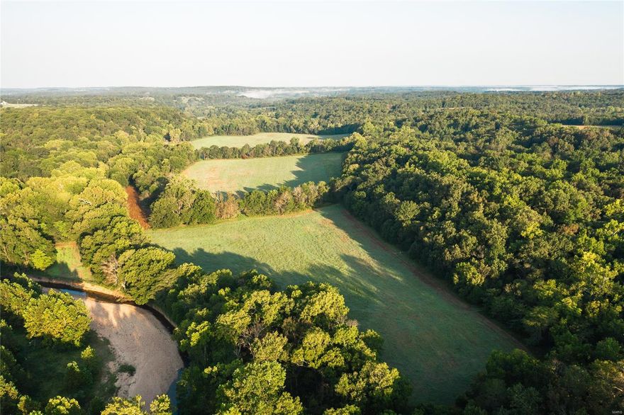 Broken Arrow Ranch is the epitome of a true hunting destination. 443 +/- acres loaded with large numbers of deer and turkey. With 85+/- acres of open and 55 acres of fertile bottom fields converted back to row crop. The very impressive and vast Oak and Walnut timber throughout the property has been valued at well over $200,000 with full appraisal in process. Atwell creek meanders through the center of the property. The 3 bed, 2.5 bath lodge has many recent updates, two large fireplaces, and stunning views overlooking the big bottom fields and creek. As many as 33 deer and many more turkey have been viewed from the sun porch at one time and wildlife in the yard is a common occurrence. Five outbuildings consist of two large hay barns, implement shed, smoke house and horse barn with three horse stalls. 60 fertile acres are currently leased for row crop with the remainder in established food plots and bedding. Three new Banks Stump hunting blinds included with the sale.