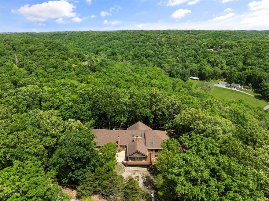 SPECTACULAR ranch home on 13.6 acres of wooded paradise in Wildwood. This custom home features a full-brick elevation, 2 car side entry gar, 4 beds, 4 baths w/3,846 sq ft +/-of living space & 725 sf Barn. Enjoy a large center island kitchen w/tile flrs, abundant cabs,& sub-zero fridge w/large adjoining bkfst rm w/wood flrs, wood burning stove, & custom oak plan desk. Family rm w/vaulted wood beam ceiling, skylights, wet-bar, wood flrs, flr-to-ceiling brick double FP to spacious tile flr garden rm w/3 walls of windows, lots of natural light, & separate zoned HVAC. Master suite w/wood flrs, walk-in closet, and luxury master bath w/jetted tub, sep shower, double vanity sinks, & a skylight. 2 add'l bedrooms, formal dining room, and laundry complete the main level. Walk-out lower level w/ 4th bed rm w/bath & tuck under garage. The L.L. has lots of potential for you finishing touches. AAA Rockwood schools. Close proximity to Rockwood Reservation, Hidden Valley, I-44,& Wildwood amenities.