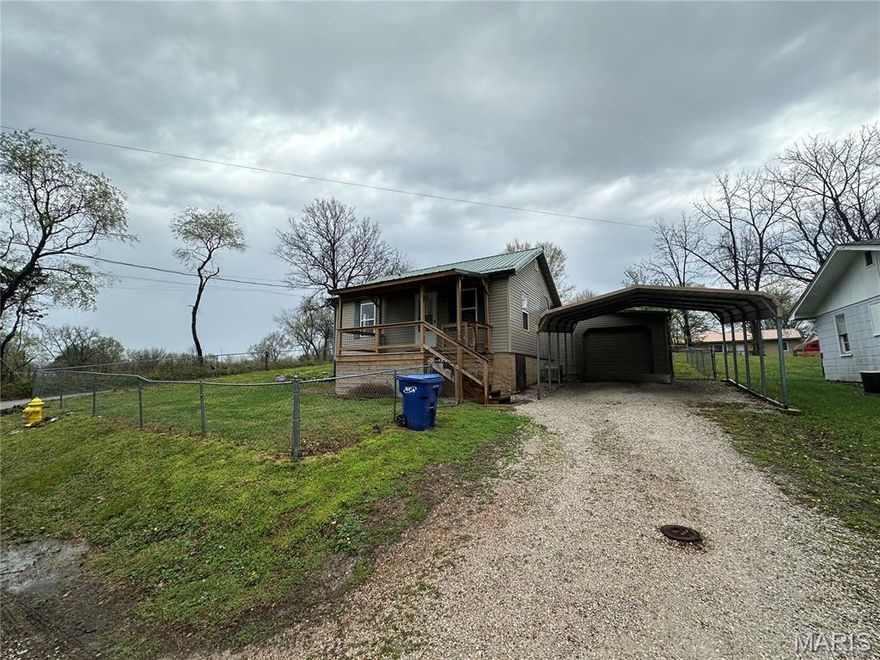 This property features a 2-bedroom layout, adaptable to 3 bedrooms, and includes 1 bathroom, benefiting from a prime corner lot location with proximity to local amenities. The interior flow starts with the dining room, which leads into the kitchen and then the living room. The hallway, accessible from the dining room, features the first bedroom to the left, the bathroom centrally located, and the primary bedroom to the right, which includes the option for a third bedroom or a spacious walk-in closet. The laundry area is situated beyond the walk-in closet, linking to the living room. The attached garage provides direct access to the living room and the fully fenced yard