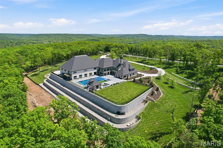 New Price. New Possibilities!  A rare Ozark Mountain compound, 300 Ridgecrest Drive is a Modern European estate set on more than 10 private acres in Saddlebrooke, Missouri, surrounded by the pristine beauty of Mark Twain National Forest,and hosting multiple outbuildings and endless amenities. 

Completed in 2023, the property offers a 7,920-square-foot residence and a remarkable 5,700-square-foot sports and entertainment pavilion with an NBA-rated basketball court, gym, and flexible event space.

Architectural materials of stone, brick, timber beams, and reclaimed wood are paired with advanced smart-home automation, magnetic-lock security, and automated blinds and screens. Inside, soaring volumes, multiple chef’s kitchens, refined finishes, and gracious entertaining spaces are complemented by a private theatre and arcade.
The primary suite is a tranquil retreat featuring a fireplace, spa bath, and sunroom with a private plunge tub and a swing bench. Furnished with Restoration Hardware pieces, the home embodies warmth, elegance, and contemporary comfort.

Outdoor living rivals a private resort with a 70-foot beach-entry pool, 12-person spa, pool house, firepit lounges, and a fully equipped outdoor kitchen with pizza oven, commercial grill, and refrigeration. Additional features include RV accommodations, a motorized gated entry, expansive motor court, and a private go-kart track. Just minutes from Branson, Springfield, and Table Rock Lake, this exceptional estate offers a rare blend of privacy, recreation, and luxury.