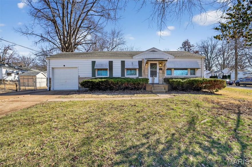 Classic single-story home set on a spacious lot with mature trees and a wide driveway leading to the attached garage. The interior features hardwood flooring throughout much of the main living areas, crown molding accents, and large windows that provide abundant natural light. The kitchen offers rich wood cabinetry, ample counter space, and black appliances, with convenient access to adjacent dining and living spaces. Bedrooms include hardwood flooring and neutral finishes, while the bathroom features a tub and shower combination with extended vanity space. A finished lower level provides additional flexible living or recreation space along with storage areas and utility access. Outdoor highlights include a covered and screened patio area overlooking the backyard, offering a comfortable space for relaxing or entertaining.