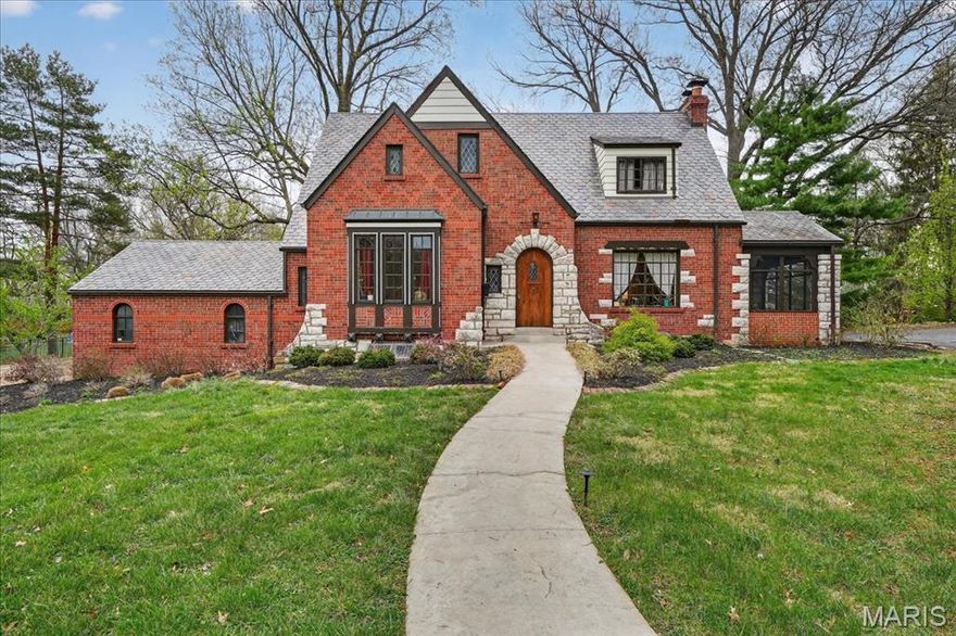 Step into timeless elegance with this spacious brick and stone Tudor-style home perfectly situated on a beautiful half-acre level lot in the highly sought-after Bellerive Acres.  This charming 3-bedroom residence showcases classic architectural details throughout, including a graceful curved staircase, rich hardwood floors and a stunning stone fireplace that anchors the great room. Character abounds with stained glass accents, box windows, original millwork, elegant arched doorways and an abundance of natural light. This home is designed for both everyday living and entertaining.  The French doors in the great room lead to the screened porch which is the perfect spot to unwind at the end of the day.  The eat in kitchen offers a butler's pantry, two additional pantries, granite counters, stainless appliances and a breakfast nook as well as additional space that can be used for a drop zone. The finished lower level, complete with durable terrazzo flooring, offers additional room for recreation, hobbies or gatherings.  A two-car garage adds convenience, while the expansive lot provides plenty of outdoor space to enjoy. And what's not to enjoy about a large yard, a maintenance free deck, a hot tub and a firepit area? Fun fact - slate tile roofs such as this one lasts anywhere from 75-200yrs old?  And this beauty is only 13yrs old! This is a rare opportunity to own a home that beautifully blends historic charm with functional living.