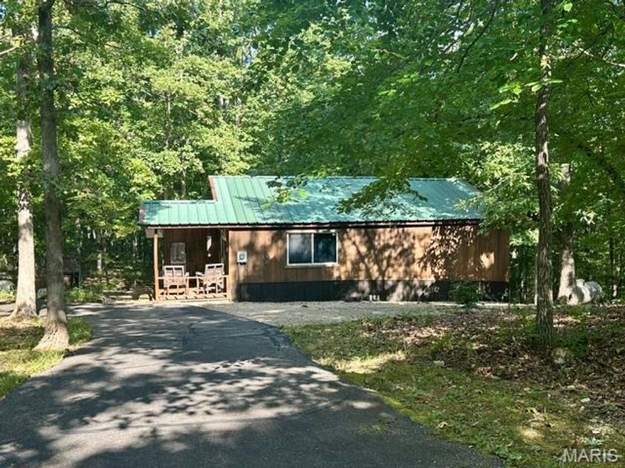 Tucked away on a quiet 5.73-acre lot, this charming 2-bedroom, 1-bath cabin offers the perfect blend of rustic character and modern updates. Located just half a mile from Lost Creek Boat Ramp and Lost Creek Nature Trail, this is a rare opportunity to own a peaceful retreat close to nature and recreation.
Property Highlights include recently updated with custom woodwork and reclaimed wood throughout. Spacious covered porch and carport for all-weather convenience.  Expansive patio area with a built-in outdoor fireplace—perfect for relaxing or entertaining. Unique half-paperclip-shaped asphalt driveway provides easy access and ample parking. Secluded setting offers privacy and quiet, yet minutes from the water and hiking. This one-of-a-kind property is ideal as a weekend escape, Airbnb, or full-time residence for anyone seeking rustic charm and natural beauty and is just minutes from Wappapello Lake, restaurants, camp grounds, shopping and more! Don’t miss your chance to own a handcrafted getaway near the lake! Listing Agent Related to Seller.