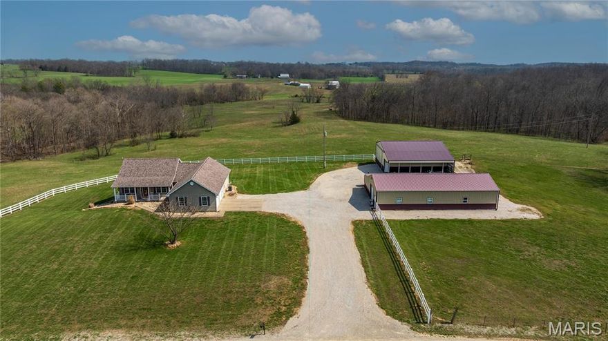 Located in the rolling hills of Perry County, this stunning 25-acre farm offers the perfect opportunity to live out your dream country side lifestyle or expand the one you already love.
At the heart of the property sits a beautiful ranch-style home featuring nearly 3,100 square feet of living space, including 5 bedrooms and 3 full bathrooms. The main level features an inviting entry foyer that opens into a spacious living area with vaulted ceilings. Additional highlights include a separate dining room and a kitchen with a breakfast nook and bar seating. The primary suite offers a recently updated en-suite bathroom complete with a freestanding soaking tub. Two additional bedrooms and a full bathroom complete the main floor. A full walk-out basement provides the other 2 bedrooms and full bath, additional living and entertaining space, complete with a bar area. And outside? Enjoy the serene views on either the covered front porch or the covered back deck that expands your living space. As an added bonus the 2 car oversized garage is equipped with heated floors. 
The acreage is thoughtfully set up with perimeter fencing perfect for running cattle, roaming horses, recreation, or even creating your own private lake. Standout features include a 30x60 insulated shop with a half bath, bar area, and horse stall. Additionally a 40x45 outbuilding (built in 2020) suitable for equipment storage or workshop use. Both structures feature covered lean-to additions for more storage.
Conveniently located approximately 10 minutes from Perryville and 30 minutes from Cape Girardeau, this property offers a rural setting with convenient access to nearby amenities. Space, privacy, and opportunity all wrapped into one incredible property.