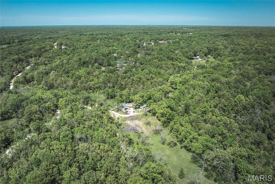 Located just minutes from the popular Bennett Spring Trout Hatchery, this unique 16-acre property near Lebanon, MO offers a rare mix of natural beauty and development-ready infrastructure. The land features two creeks, stunning cliff faces, and natural rock shelters, creating a picturesque Ozarks setting. Currently set up as a commercial property, it includes 12 RV hookups with power and water, a bathhouse with men’s and women’s restrooms and showers, and a remodeled mobile home with a metal roof—perfect as a full-time residence or rental unit. The impressive 31x61 garage features a loft, large shop space, and high ceilings—ideal for storage, workspace, or expansion. Whether you're looking to run a campground, start a business, or enjoy a private homestead in a prime location, this property offers endless potential.