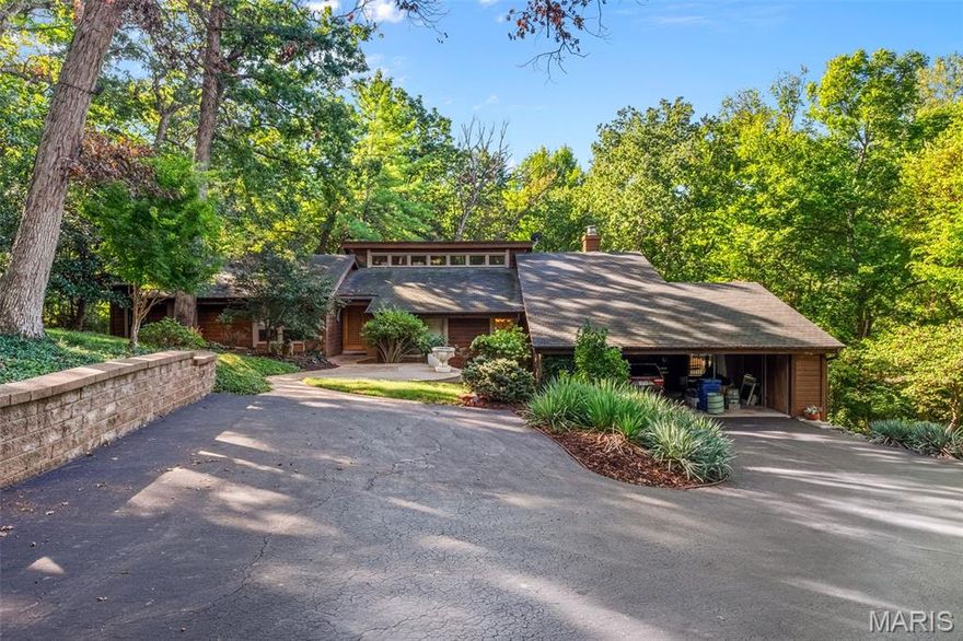 This is a unique find! A private gated drive leads you to this contemporary ranch set on 3.18 private acres with natural wooded land and bountiful gardens right in the heart of Chesterfield! Soaring vaulted teak ceilings, cedar beams, and floor-to-ceiling windows frame lush views at every turn. An organic entry foyer welcomes you, complete with an atrium, water feature, and access to a loft space. 
On the main level, the expansive primary suite walks out to a wrap around cedar deck and offers a primary bath featuring a double sink vanity, sunken Jacuzzi whirlpool, pellet stove, and walk-in shower — the ultimate in relaxation and style. Entertain easily with an open layout flowing from the living room to the dining area and kitchen, while a great room with a stone fireplace opens onto newer multi-level cedar decks with a built-in spa overlooking the wooded surroundings.
The lower level walk-out includes a family room, rec room, three additional bedrooms, a full bath, and abundant storage. Features include hardwood and travertine flooring, custom interior doors, and teak accents. Three-car covered carport, public water, private septic system, and no subdivision constraints make this property uniquely private yet accessible.
This home offers rare acreage, elegance, and serenity just minutes from Chesterfield’s amenities. Don’t miss this special opportunity.
