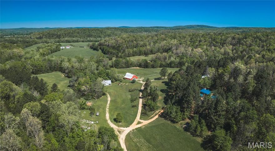 Patty Creek Farm is a truly distinctive offering, presenting the opportunity to own an established destination property in the heart of Madison County’s rolling countryside. Spanning 111.58 acres, this thoughtfully developed farm combines scenic natural features, functional improvements, and proven income potential, all set within a peaceful and private valley setting.

The landscape is anchored by the clear, spring-fed waters of Patty Creek, which wind through the property and contribute to both its beauty and practicality. Multiple natural springs supply water to several of the improvements, adding to the property’s self-sustaining appeal. The land itself is a diverse mix of approximately 94 acres of mature hardwood timber and gently rolling open areas, creating an ideal environment for wildlife, recreation, and future use. Whitetail deer and turkey are abundant, making this property equally attractive to outdoor enthusiasts and hunters.

Improvements throughout the farm have been designed with versatility in mind, supporting both private enjoyment and guest accommodations. The main residence offers over 1,500 square feet of comfortable living space, complemented by a full basement that provides additional storage and flexibility. Nearby, the Sunset House serves as a modern guest home, offering approximately 1,024 square feet of well-appointed space ideal for visitors or short-term stays.

Adding to the property’s character is the original farmhouse, dating back to the mid-1920s. Overlooking the spring-fed creek, this home offers approximately 1,128 square feet and captures the charm and nostalgia of a bygone era, reminiscent of a simpler time while still serving as a functional living space.

At the center of the property’s event capabilities is a 2,100-square-foot barn, constructed in 2010 and designed to accommodate weddings, retreats, and gatherings of all kinds. This space has been utilized for a wide range of events and serves as a focal point for the farm’s hospitality operations. Further enhancing the property’s appeal is a 357-square-foot off-grid cabin, tucked away in the timber and outfitted with a wood cook stove, offering a secluded and authentic outdoor experience.

Patty Creek Farm is currently operated as a successful retreat and event venue, hosting weddings, family gatherings, and seasonal attractions such as a Haunted Forest and Hay Maze. The property also offers overnight lodging, welcoming guests from a variety of backgrounds seeking a peaceful rural escape. This established use provides immediate income potential while leaving room for expansion, customization, or a transition to more private use if desired.

Whether the next owner envisions continuing its success as an event-driven business, enhancing its recreational offerings, or simply enjoying it as a private family retreat, Patty Creek Farm delivers a rare combination of natural beauty, functional improvements, and long-term potential. Properties with this level of versatility, setting, and existing infrastructure are seldom available, making this a unique opportunity to invest in both lifestyle and income.