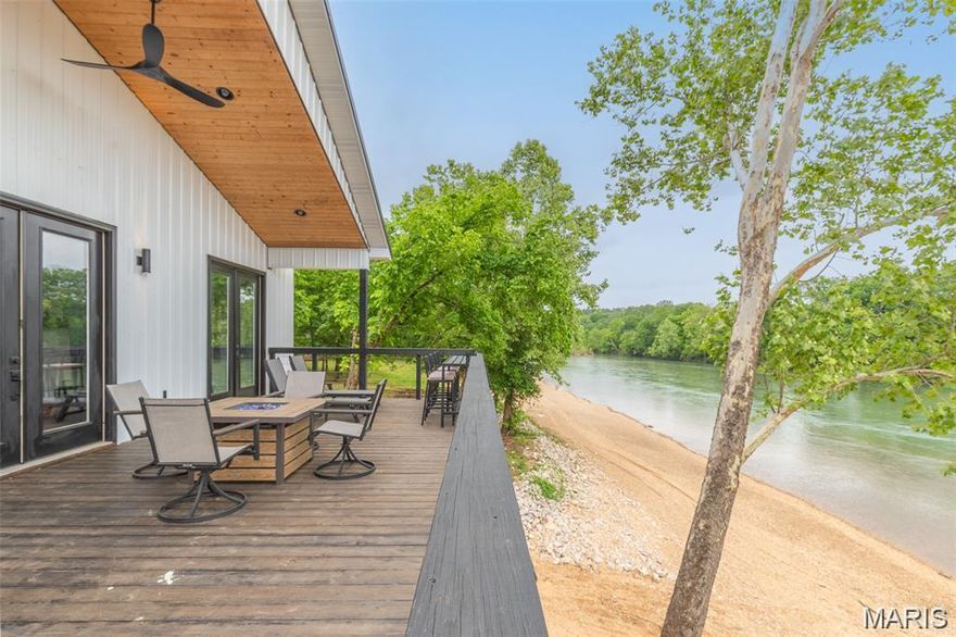Experience refined riverfront living in this exceptional 4 bedroom, 3 bath contemporary cabin overlooking the scenic Current River. Elevated approximately 4 feet above the 100 year flood plain, this .4 acre +/- property delivers both security and sweeping water views. The interior showcases black stainless appliances, a built-in microwave and wine refrigerator seamlessly integrated into an oversized granite island that anchors the kitchen and makes entertaining effortless. The open living space is highlighted by warm wood ceilings, a striking built-in fireplace, and expansive French doors that lead to a generous back deck designed for soaking in panoramic river views. Positioned along one of the river’s premier gravel bars for swimming and recreation, the property also offers two RV hookups and a covered pavilion. Ideal as a luxury getaway, income producing short term rental, or full time retreat on the water.