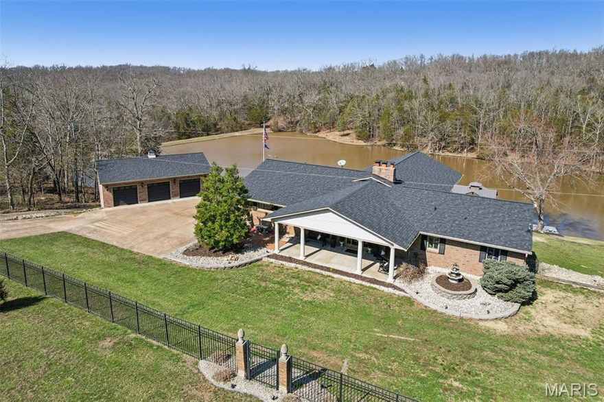 Rare opportunity just south of the Gateway City and on the doorstep of the Ozarks — the “house with the lake” on Highway 110 can now be yours. Set on more than 25 private acres, this remarkable property with fenced and gated entrance offers the kind of setting that rarely becomes available: peaceful countryside, a stunning private lake, and a beautifully designed home built to take full advantage of the surroundings.

Inside, the home features an open floor plan with a spacious living room highlighted by gleaming wood floors and a gas fireplace. The kitchen is designed for both everyday living and entertaining, with granite countertops, a center island, and tasteful backsplash, all flowing naturally into the breakfast area where a double-sided wood-burning fireplace adds warmth and character. A separate dining room provides additional space for gatherings.

The primary suite offers a relaxing retreat with a walk-in closet and spa-like bath featuring a clawfoot tub, walk-in shower, and double-sink vanity. An additional bedroom with private bath is located on the main level, while two more bedrooms are found in the walk-out lower level.

Downstairs, the finished lower level expands the living space with a large family room with gas fireplace, media area with wood burning fireplace, dining space, full bath, and even a second kitchen—ideal for entertaining, guests, or multi-generational living. A bar area with granite counters and space for a pool table creates the perfect setting for hosting.

Step outside and the true magic of the property unfolds. The spring- and creek-fed 4-acre private lake, recognized by the Missouri Department of Natural Resources as a designated “master angler” lake, offers incredible fishing, hunting, and year-round recreation. Enjoy kayaking, paddle boarding, or relaxing by the water from one of the three private docks, while trails around the lake create the perfect setting for peaceful walks, picnics, and evenings around the fire pit. 

Outdoor living is equally impressive with multiple maintenance-free decks, a screened-in sunroom, an outdoor BBQ area, and an 8x16 swim spa for year-round relaxation and exercise. A detached garage provides additional parking and storage, and the home also features geothermal heating and cooling for energy efficiency along with a brand-new roof installed in 2025.

Whether you're fishing at sunrise, enjoying a quiet walk along the lake, or hosting family and friends for a weekend retreat, this property offers a lifestyle that feels like a private resort—yet remains just a short drive from St. Louis and nearby amenities.